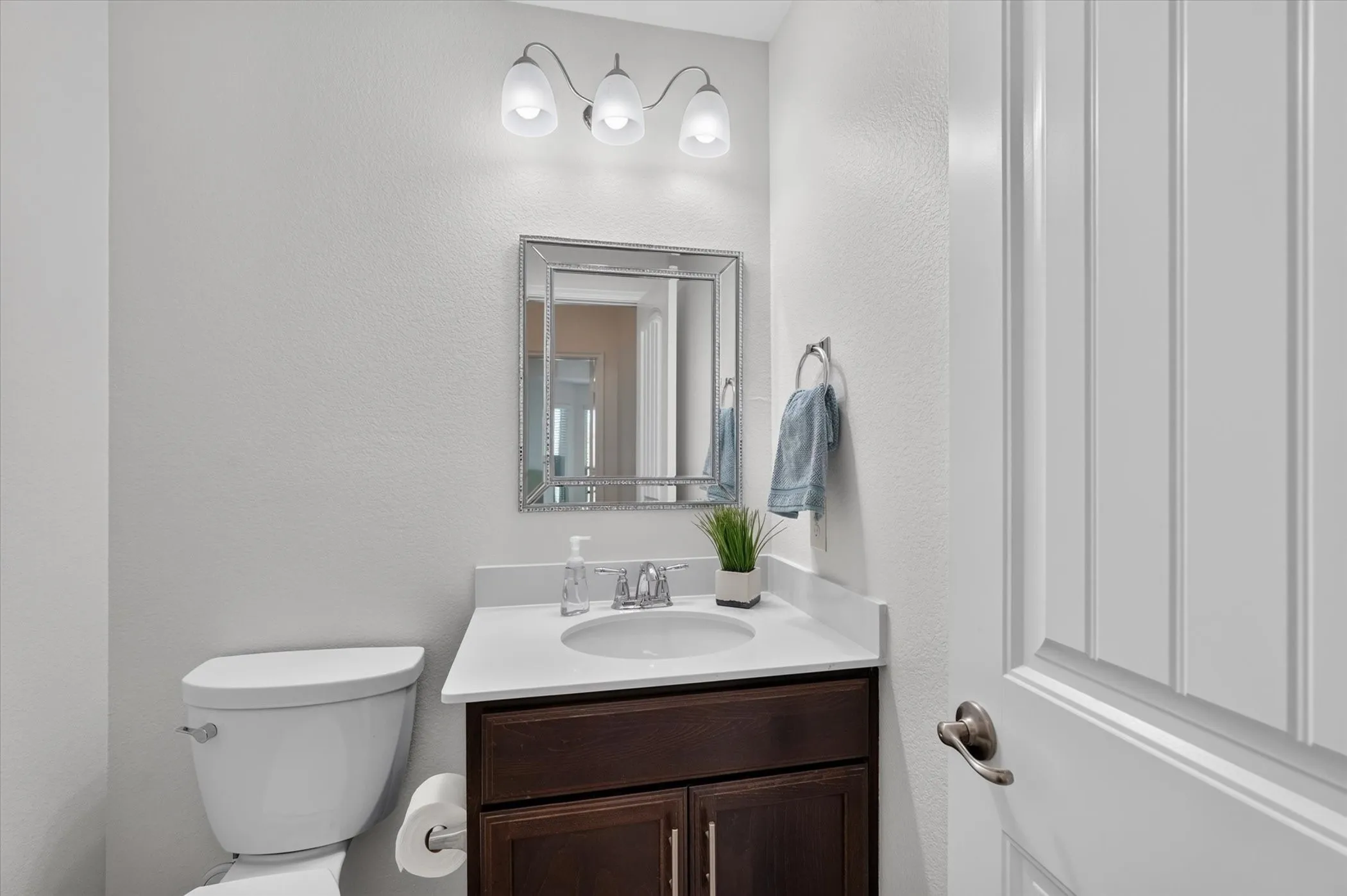 White vanity with an integrated sink, dark wood-finish cabinetry, and a chrome faucet
