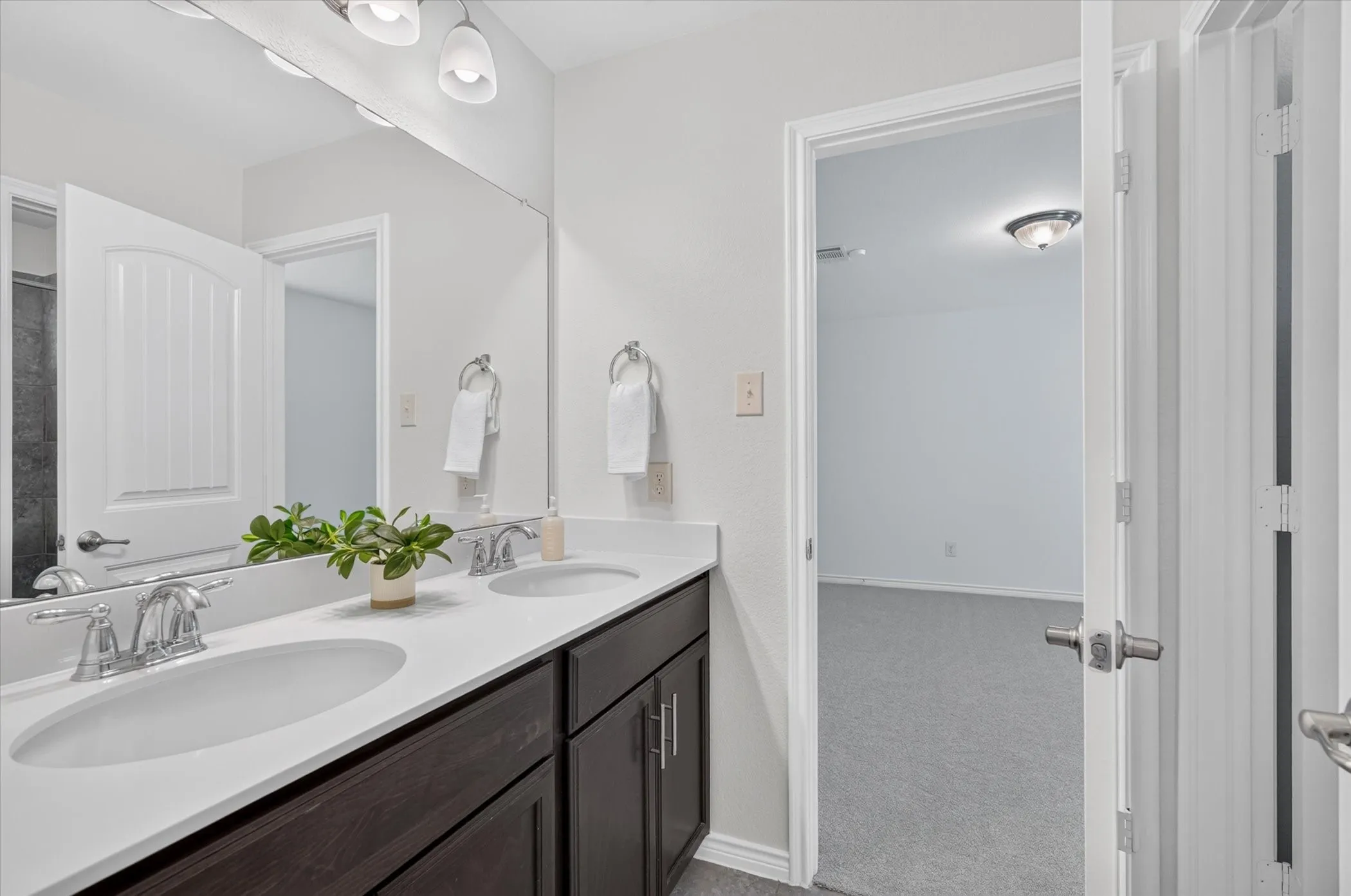 Double vanity with undermount sinks, chrome fixtures, and dark wood-finish cabinetry