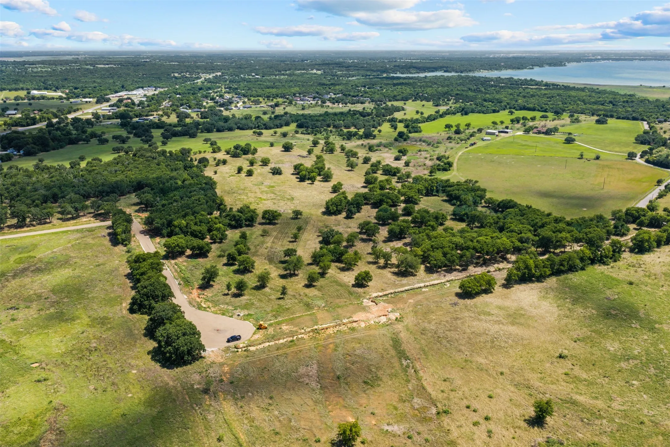 Expansive landscape featuring undeveloped land, scattered trees, and a distant body of water