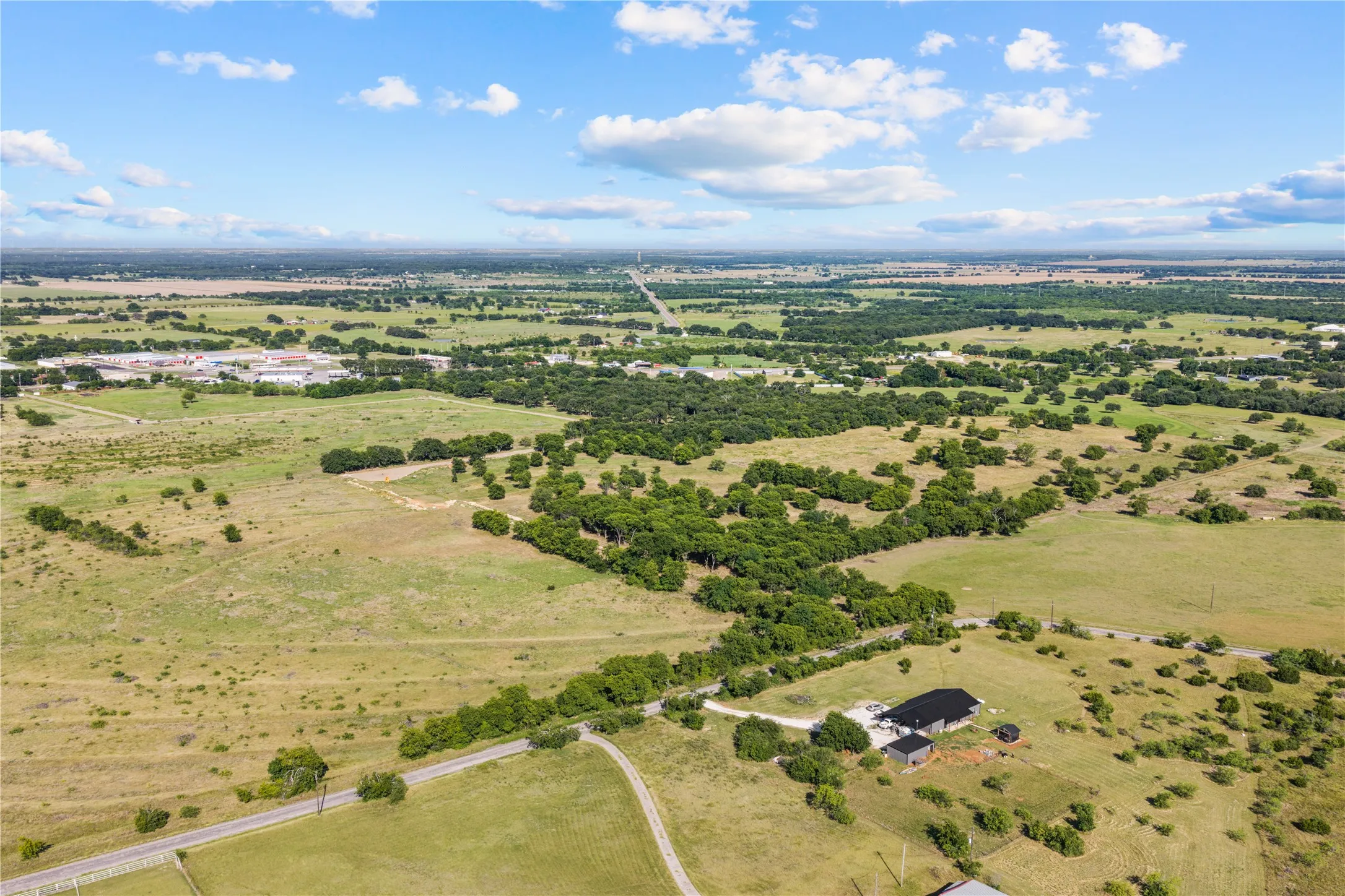 Expansive acreage featuring a single-story residence with a dark roof and a paved driveway