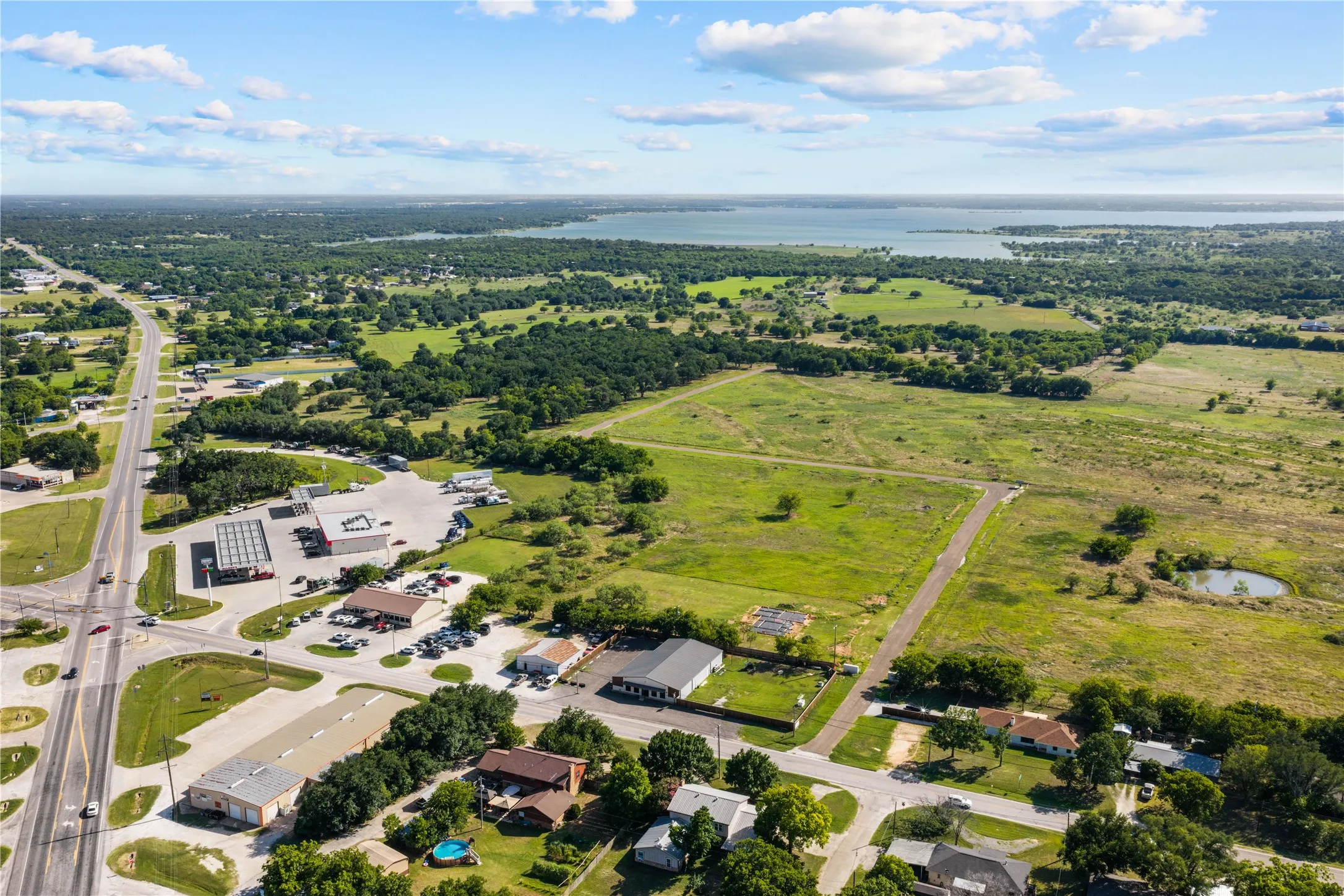 Expansive rural landscape featuring a large body of water, green fields, and established roadways