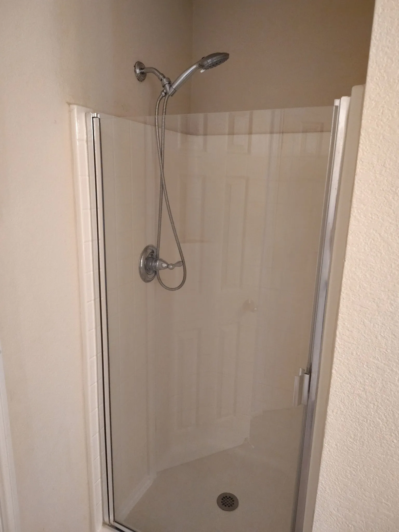 Shower enclosure with clear glass door, chrome fixtures, and built-in bench seating