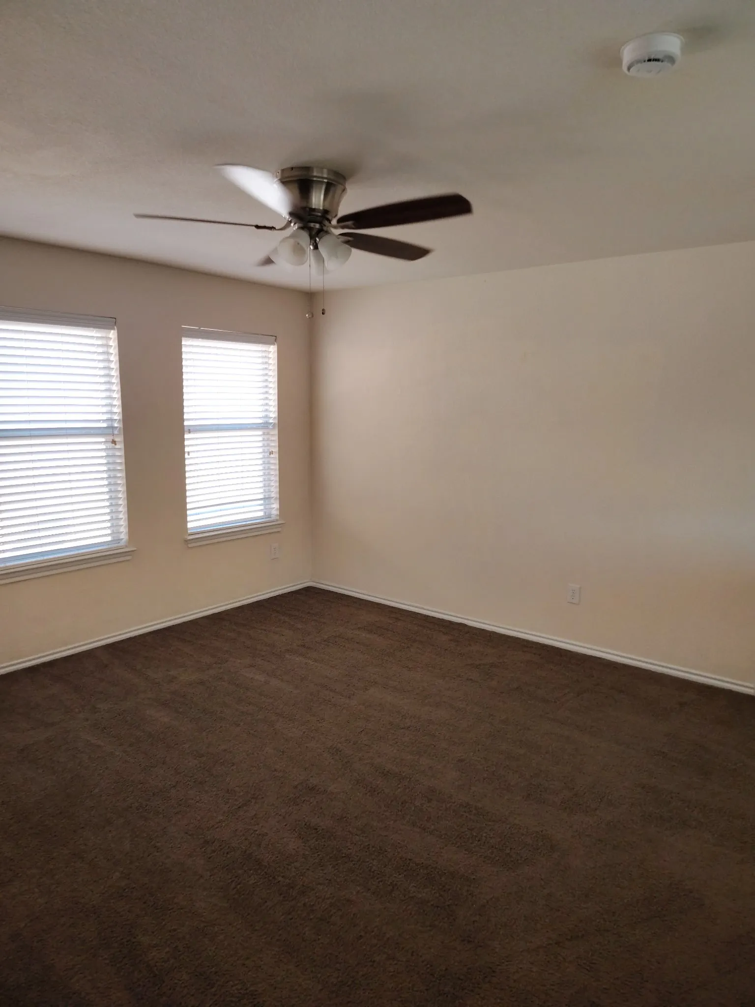 Recessed windows with blinds, ceiling fan with light fixture, and wall-to-wall carpeting