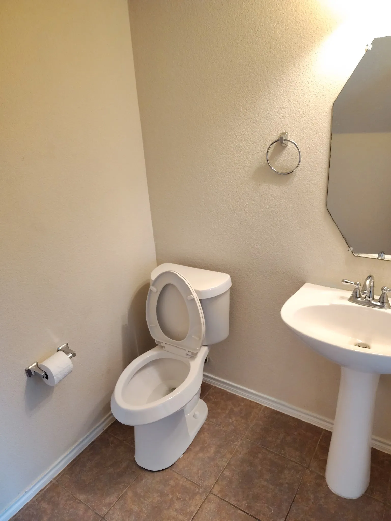 Pedestal sink with chrome fixtures, octagonal mirror, and tile flooring