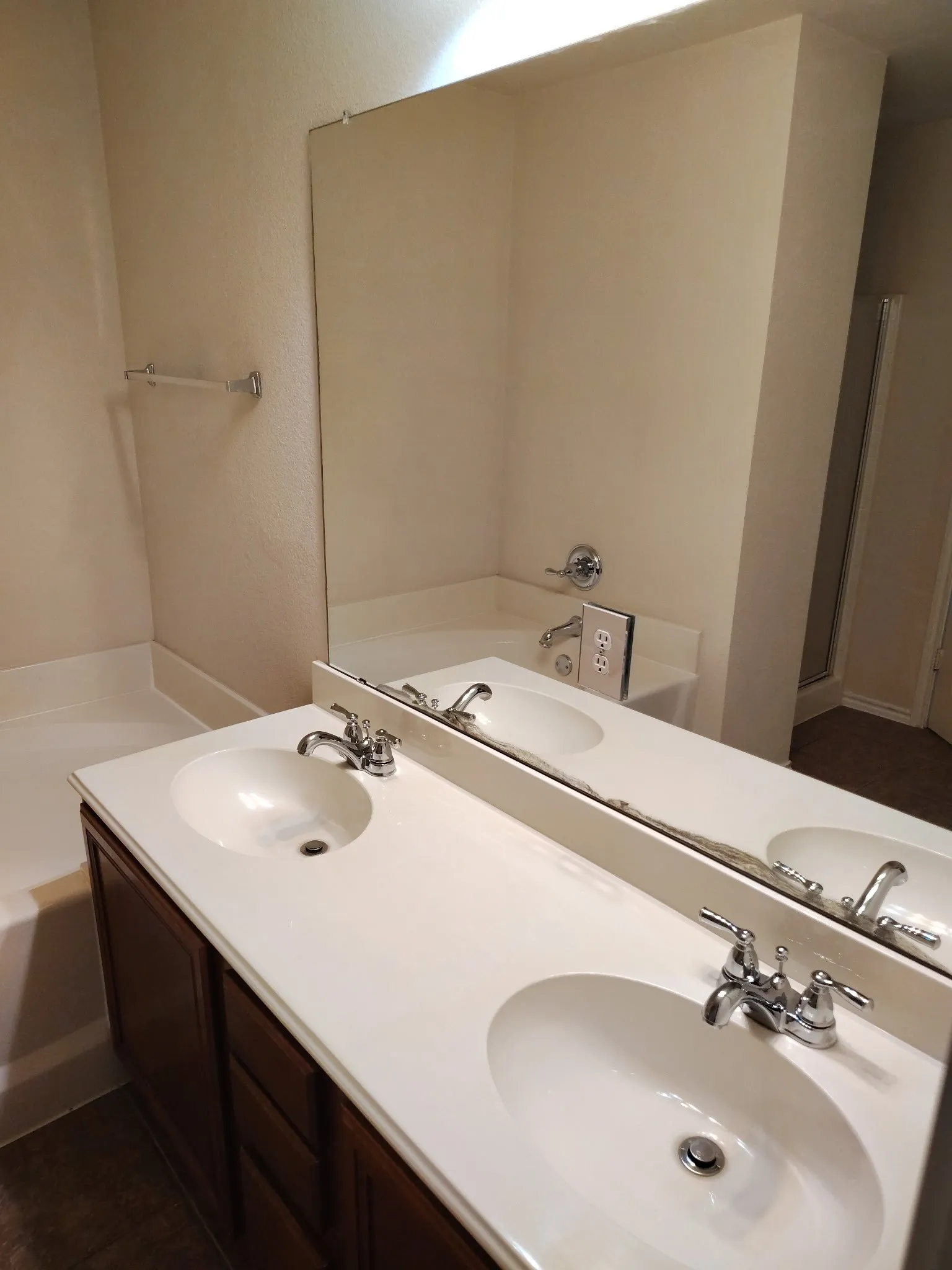 Dual vanity with integrated sinks, chrome fixtures, dark wood-finish cabinetry, and a large wall-mounted mirror