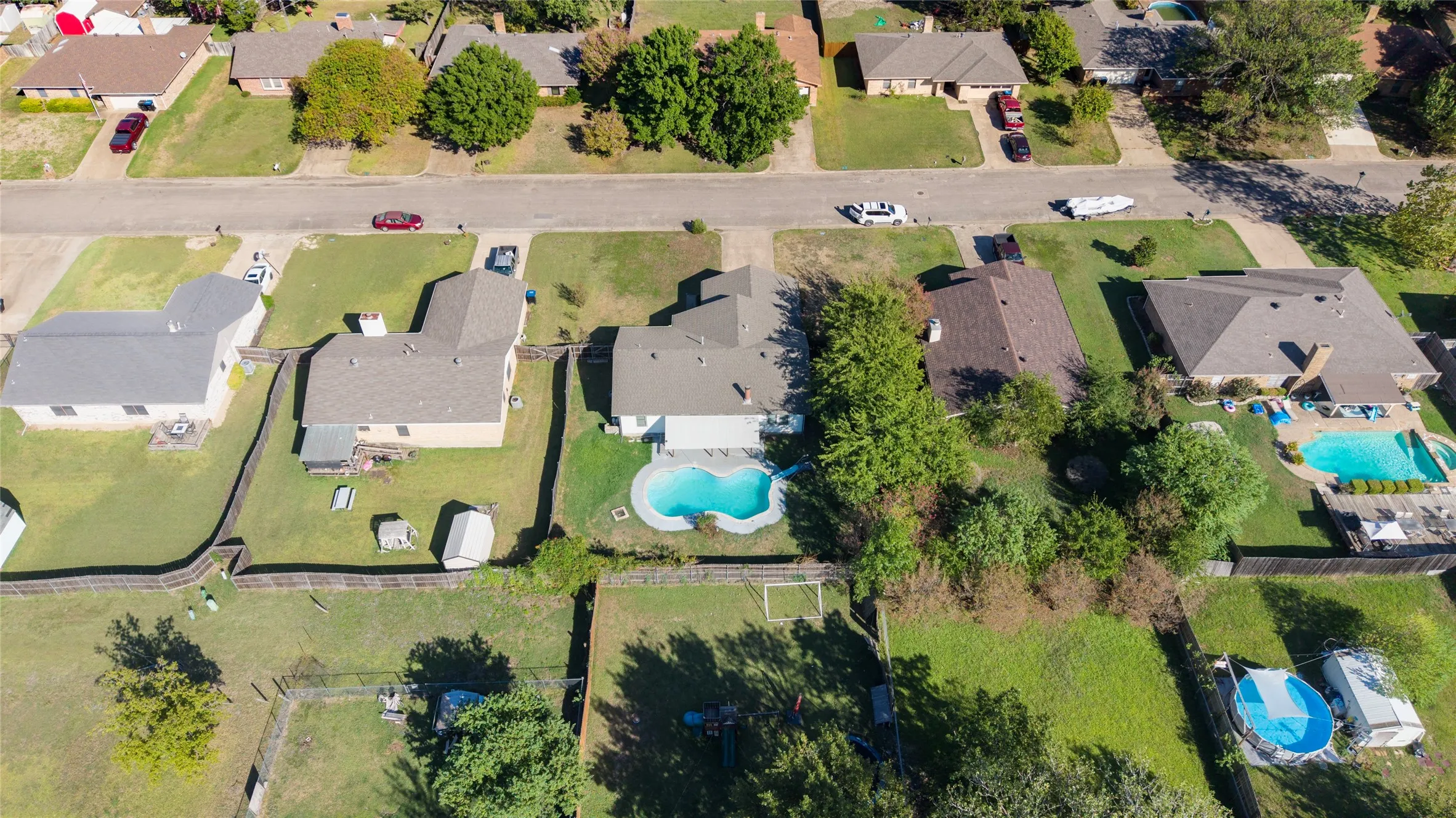 Property featuring an in-ground swimming pool, fenced yard, and an additional storage shed