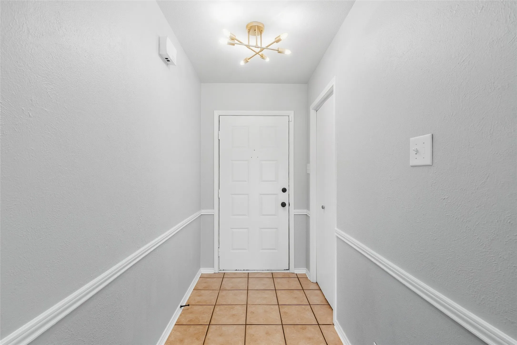 Entryway featuring tile flooring, wainscoting, and a decorative ceiling light fixture