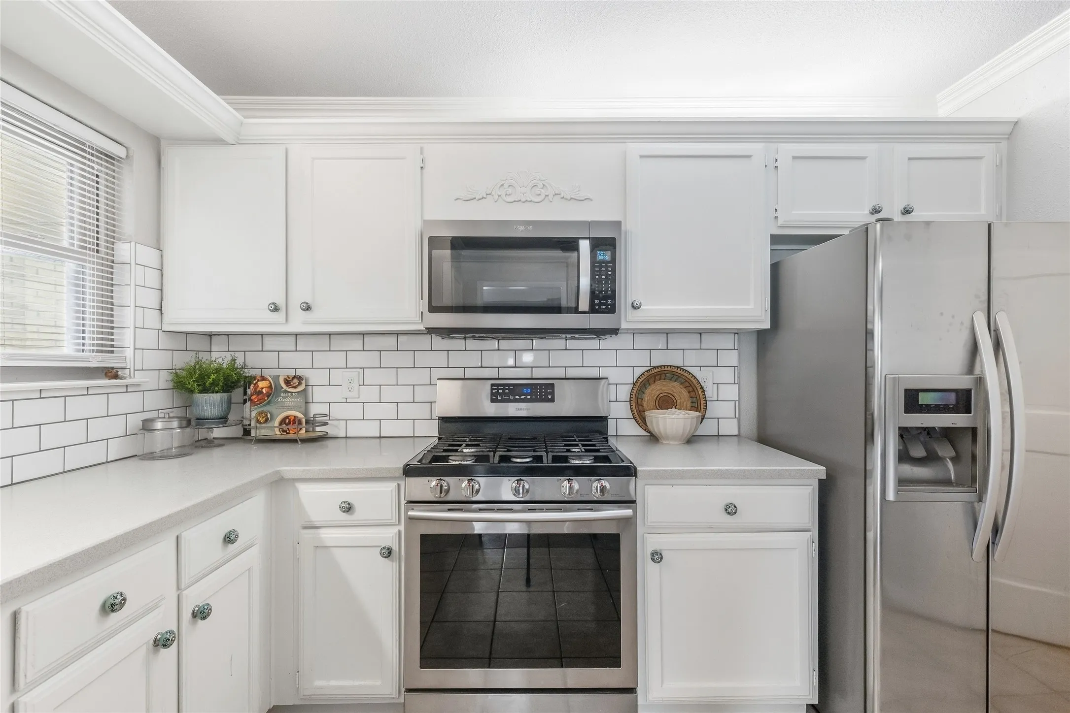 White shaker-style cabinetry, subway tile backsplash, stainless steel appliances, gas range, and extensive countertop space