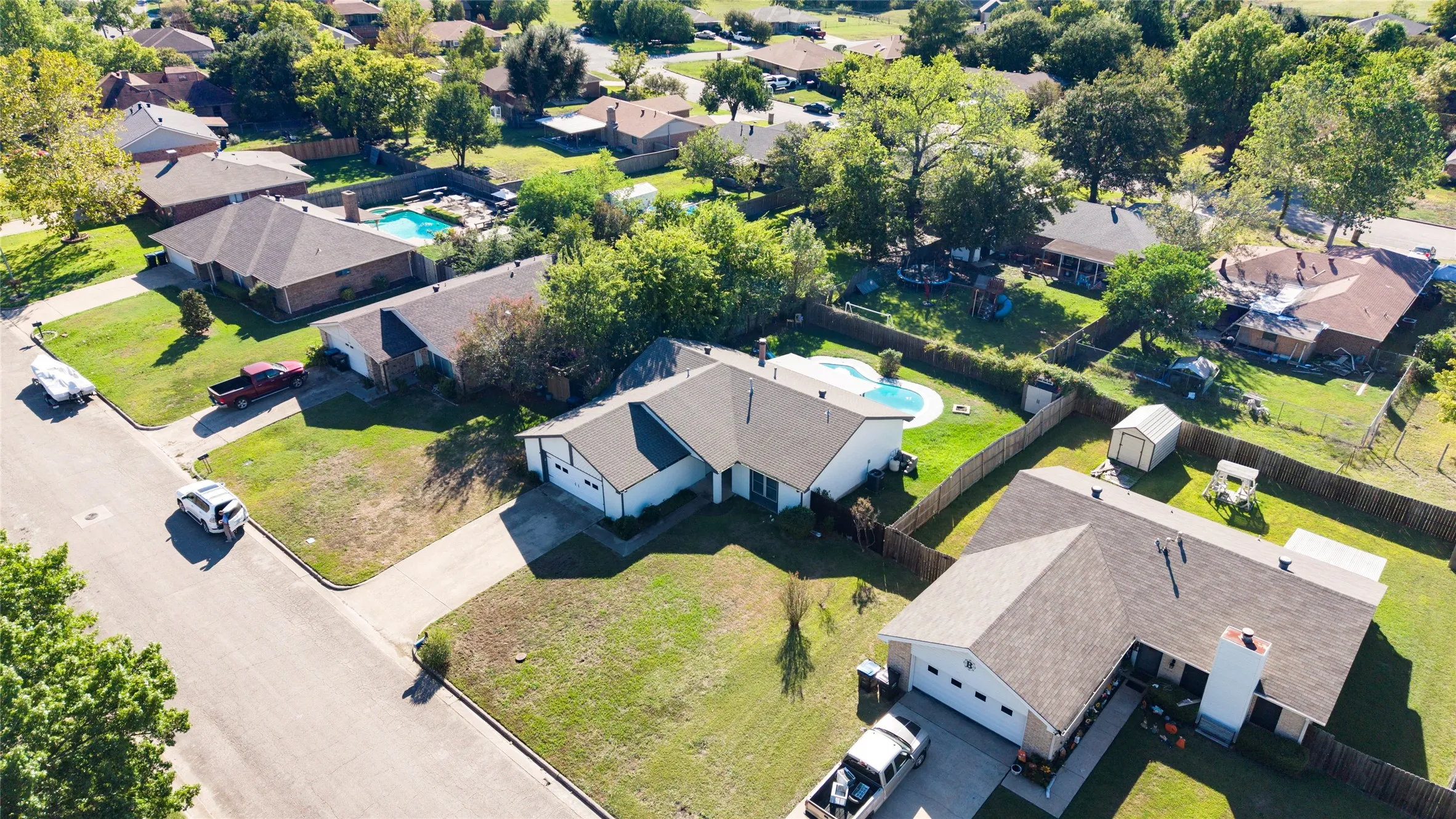 Single-story residence with an attached garage, featuring a paved driveway and a fenced backyard with an in-ground pool