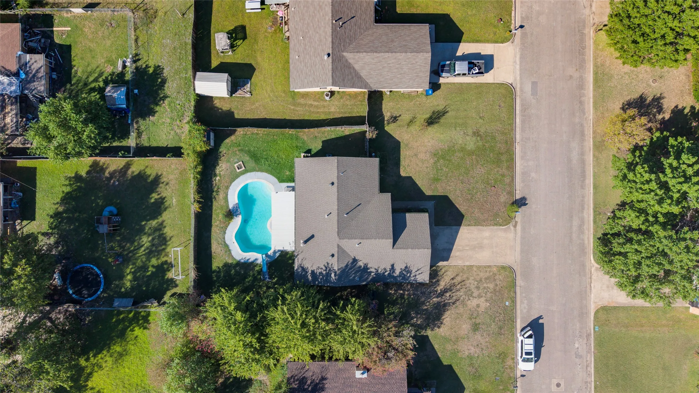 Property featuring a private swimming pool, concrete pool decking, and an expansive lawn