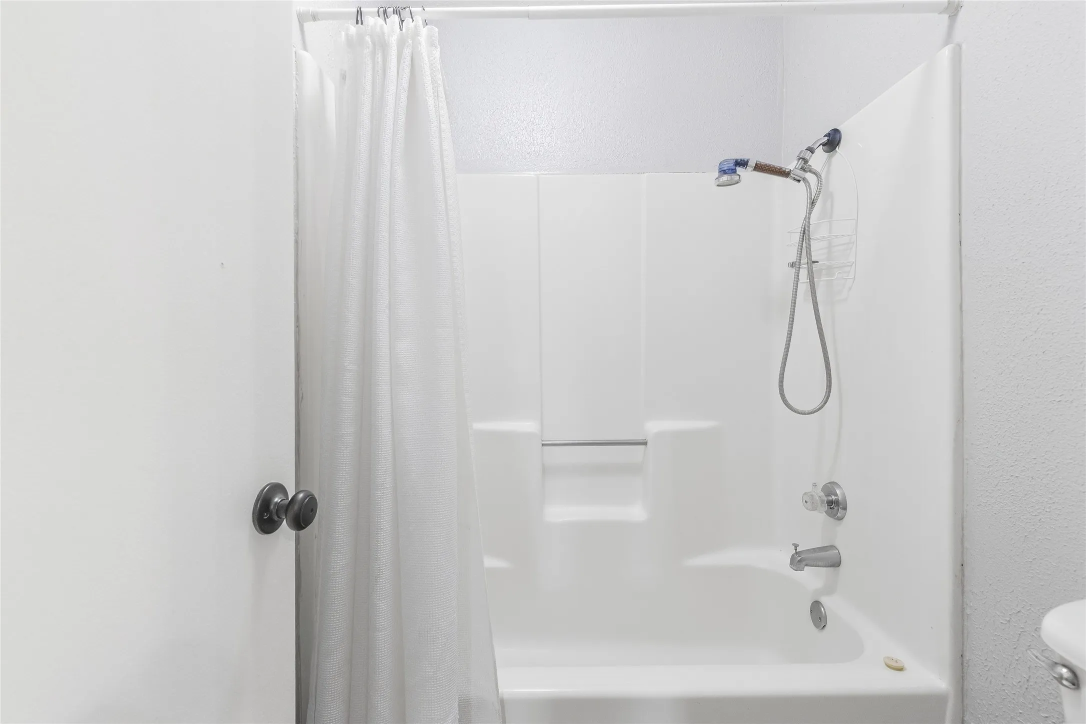 White shower-over-tub combination with a showerhead and separate handheld sprayer