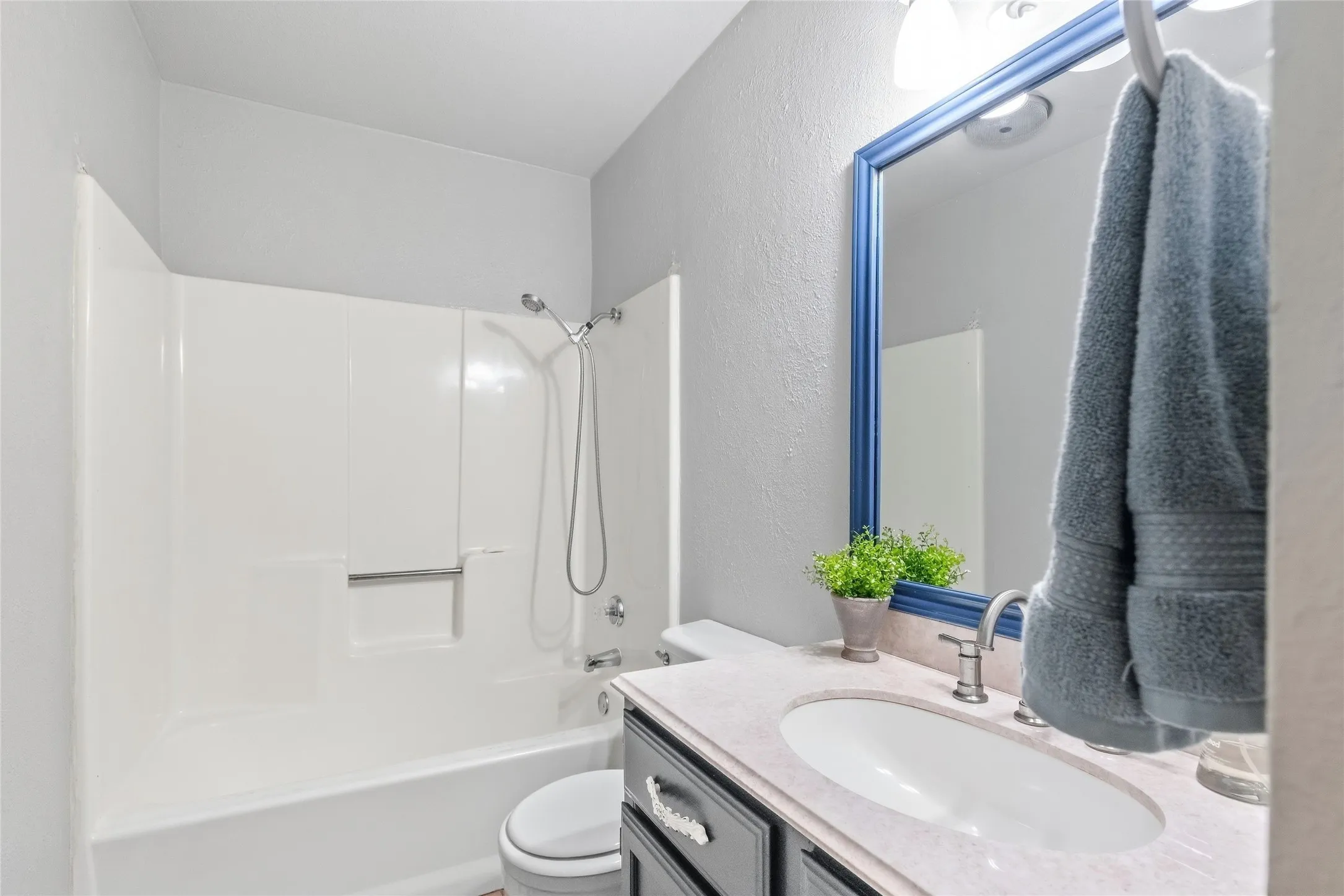 Bathroom featuring a white shower/tub combination, vanity with a built-in sink, and a framed mirror