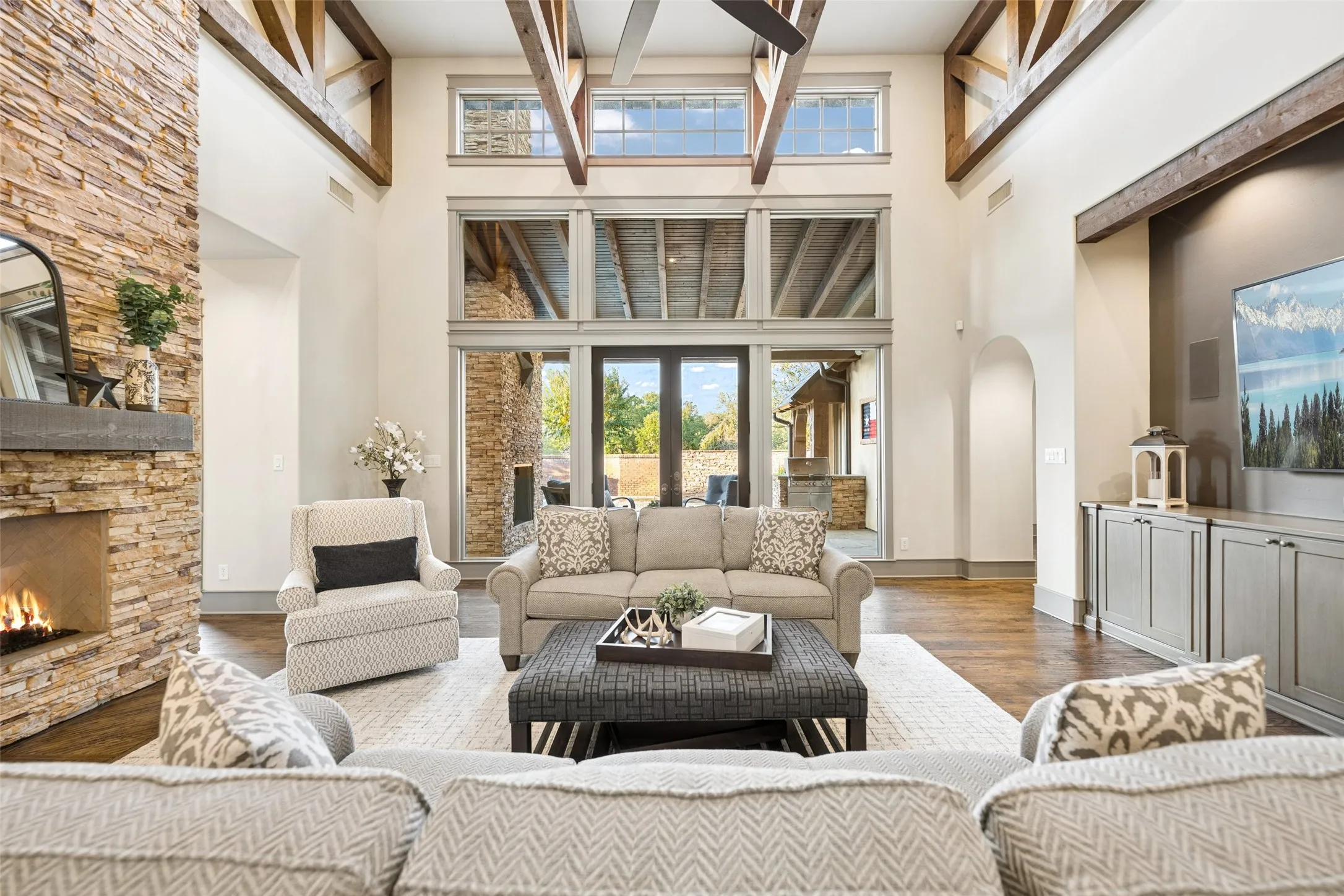 A striking two-story wall of windows and double doors floods the room with natural light and opens to the covered patio.
