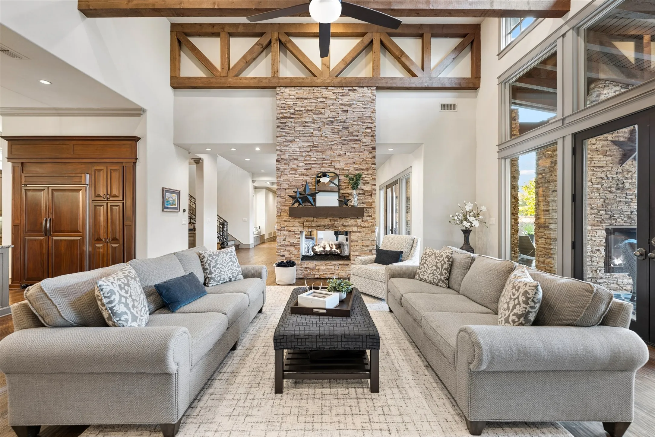 A floor-to-ceiling stacked-stone see-through fireplace serves as an impressive focal point between indoor and outdoor living.