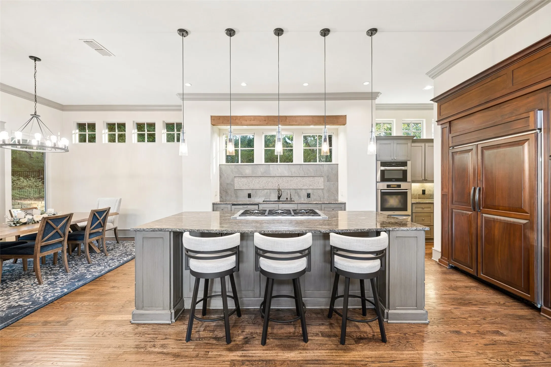 An expansive granite island with breakfast bar seating and sleek pendant lighting anchors the gourmet chef's kitchen.