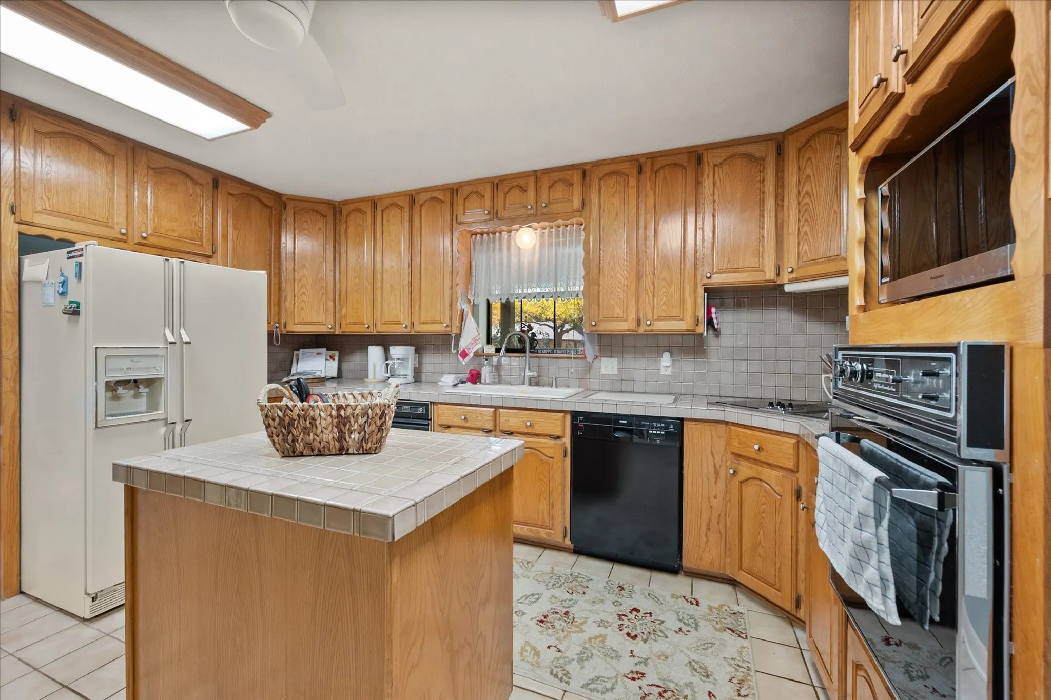 Kitchen featuring wood-finish cabinetry, tile countertops, a built-in oven, and a built-in microwave