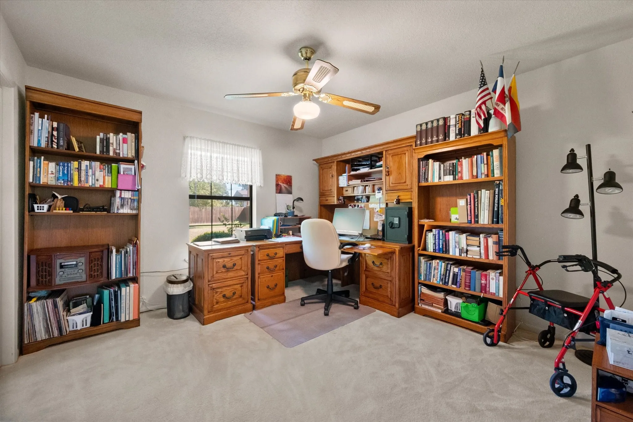 Built-in wood-finish cabinetry, wood-finish shelving, overhead ceiling fan, and window with natural light