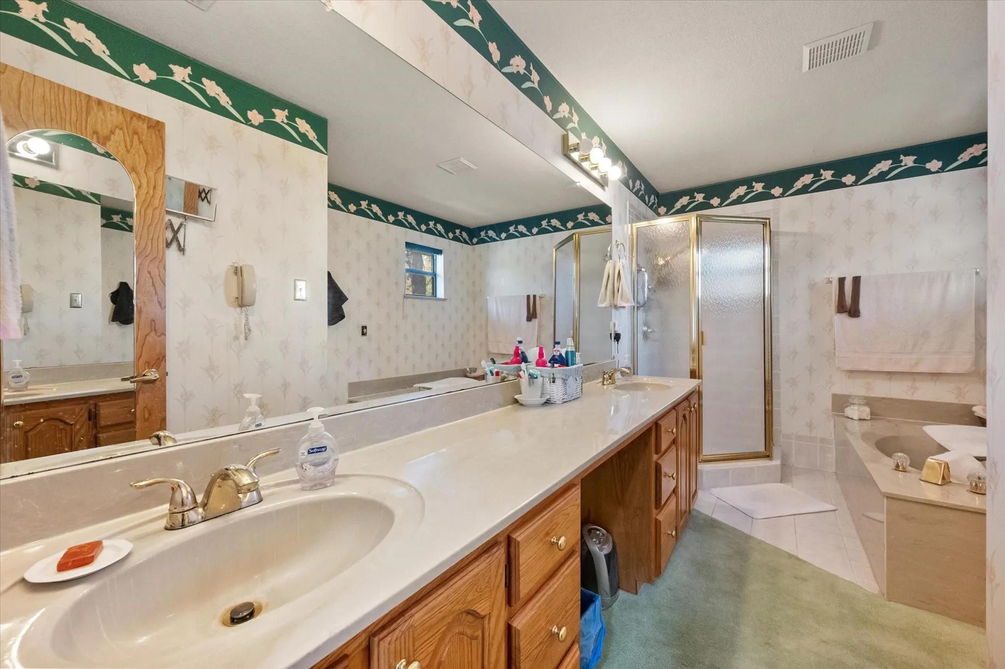 Dual vanity with wood-finish cabinetry, a built-in shower, an integrated tub, and a large wall-mounted mirror