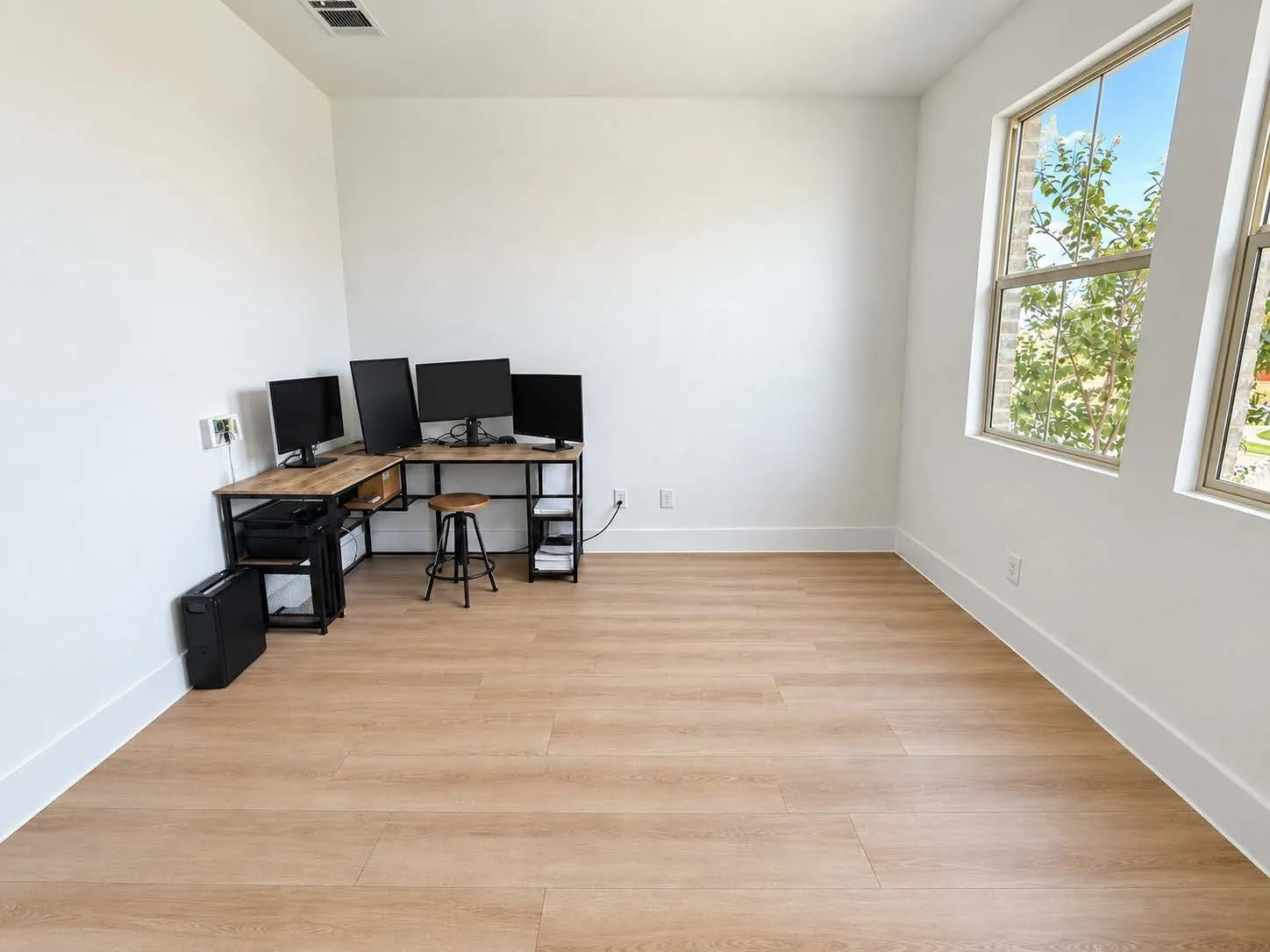 Expansive room featuring light wood-finish flooring and multiple large windows