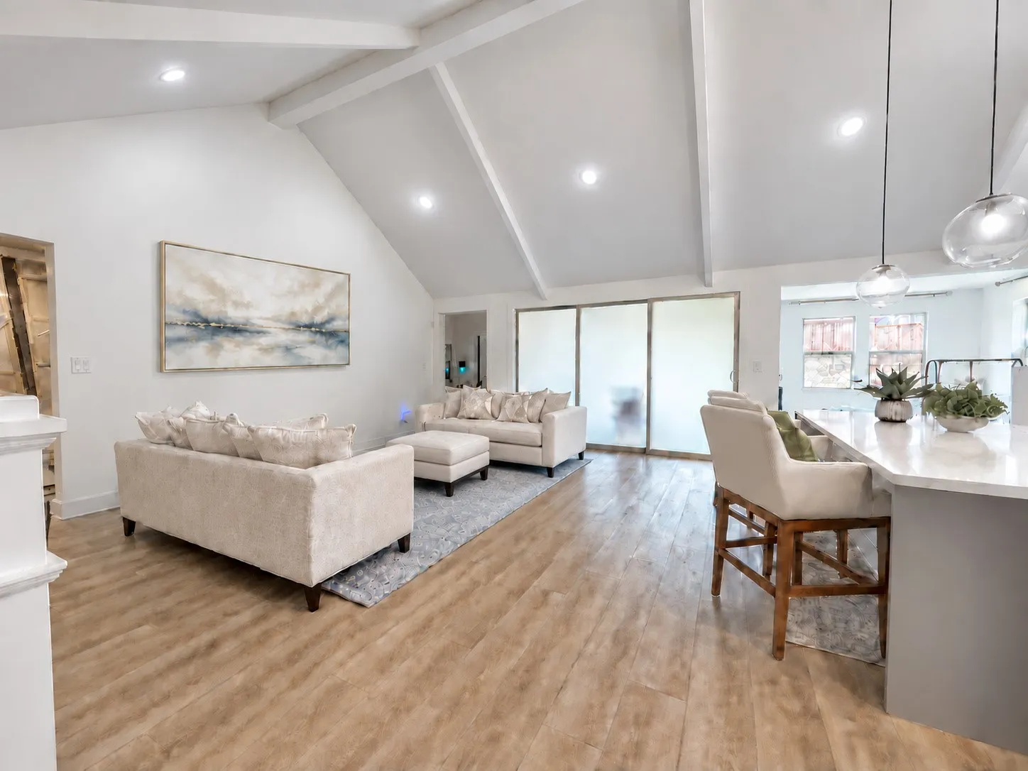 Vaulted ceiling with exposed beams, recessed lighting, wood-finish flooring, and a kitchen island with pendant lighting