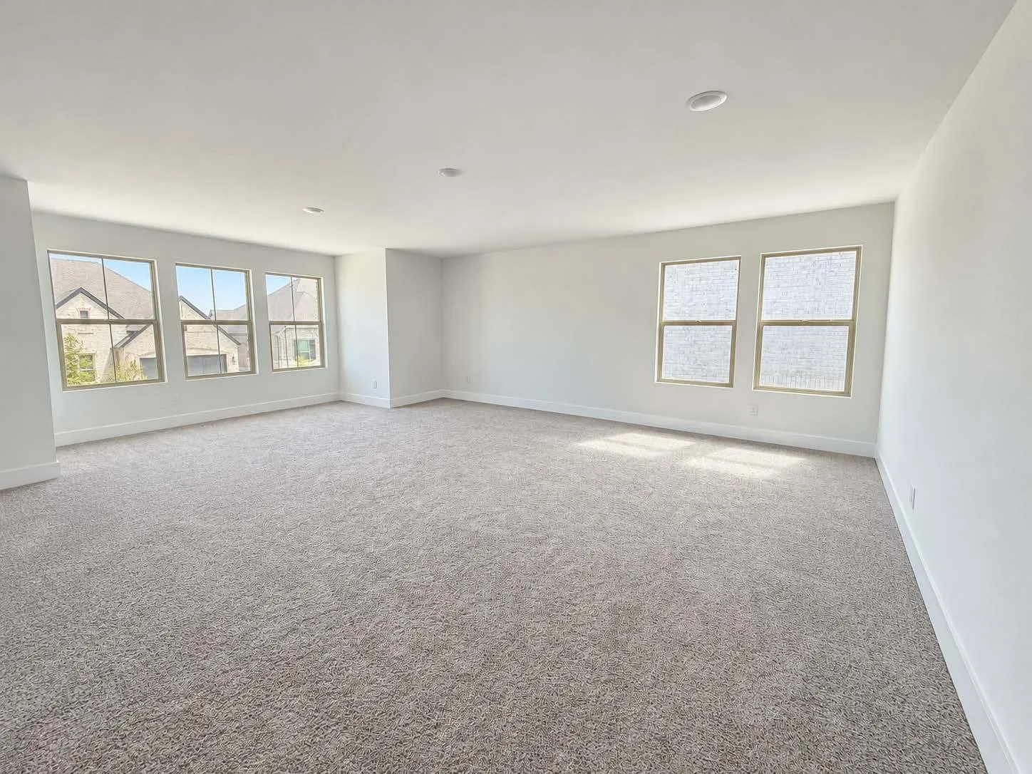 Expansive room featuring plush carpeting, multiple windows, and recessed lighting