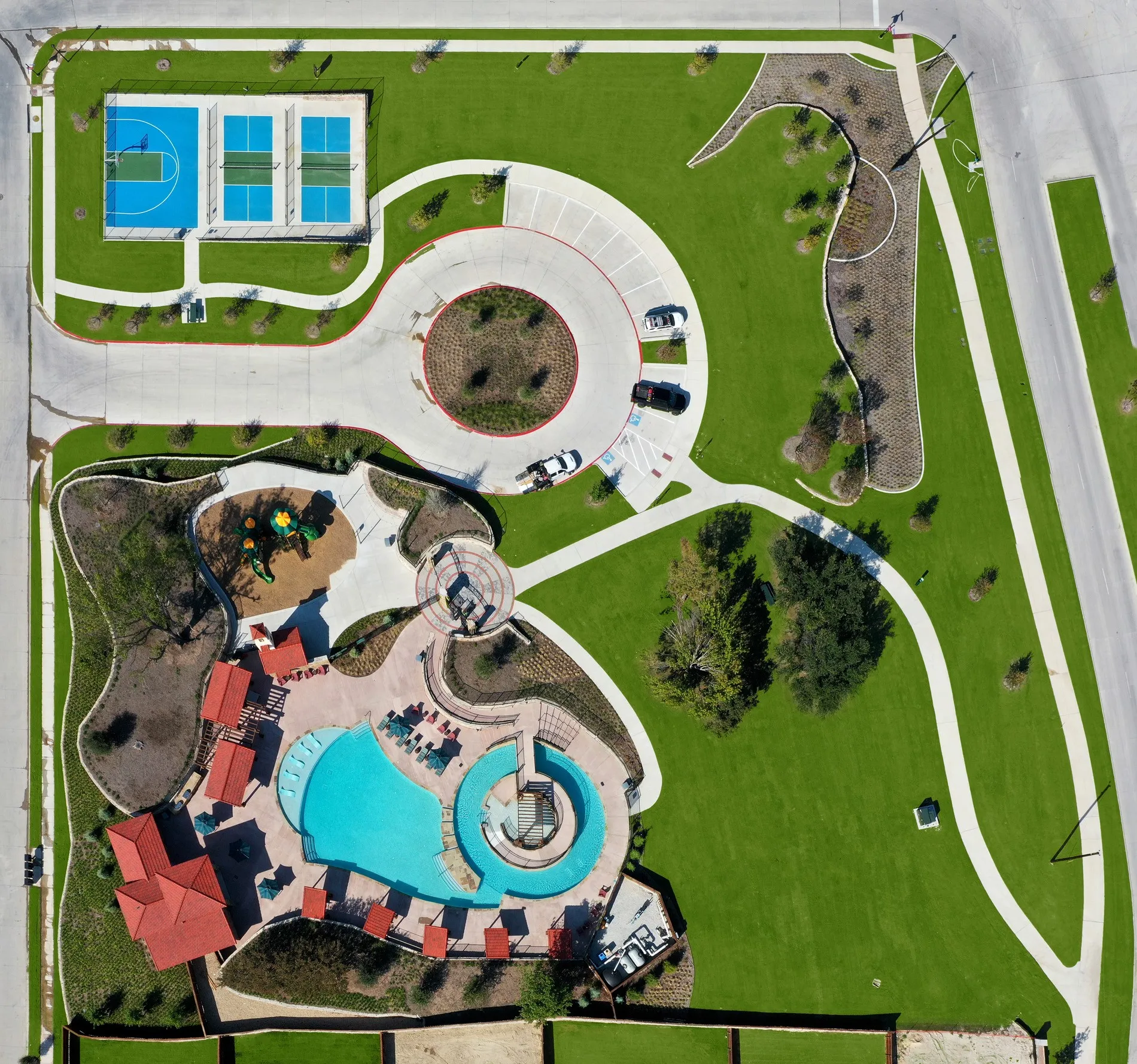 Community recreation area featuring a swimming pool, multiple sports courts, a playground, paved walking paths, and expansive landscaped lawns