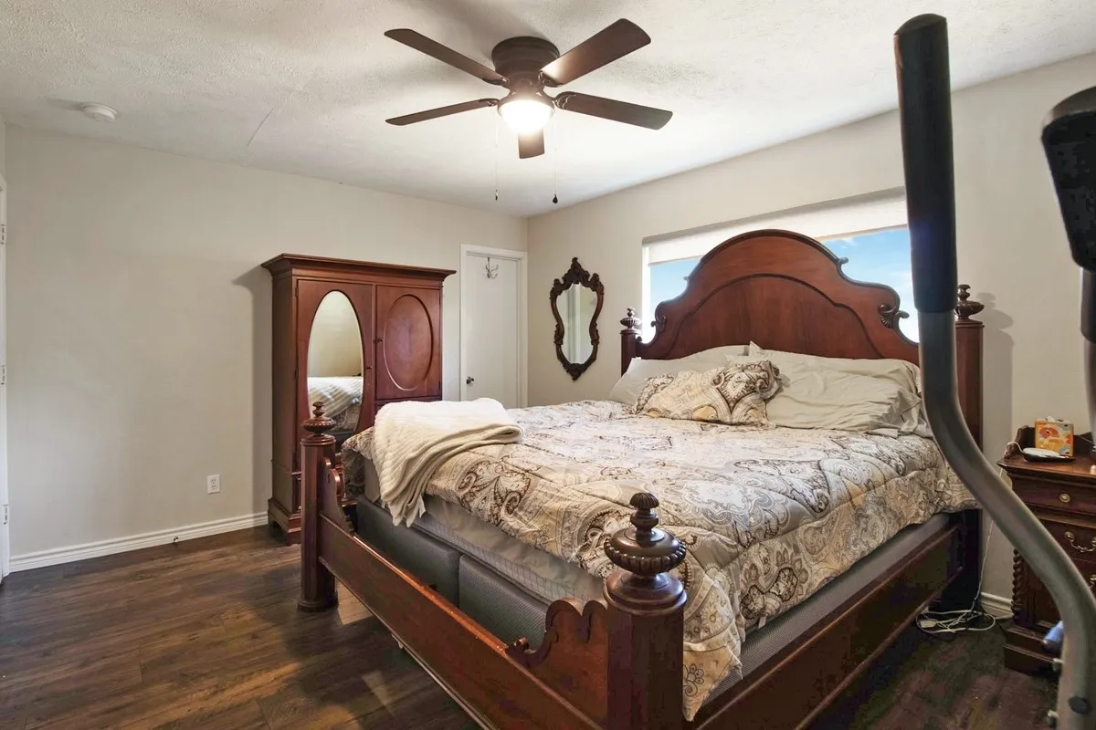 Primary bedroom with large window and ceiling fan.
