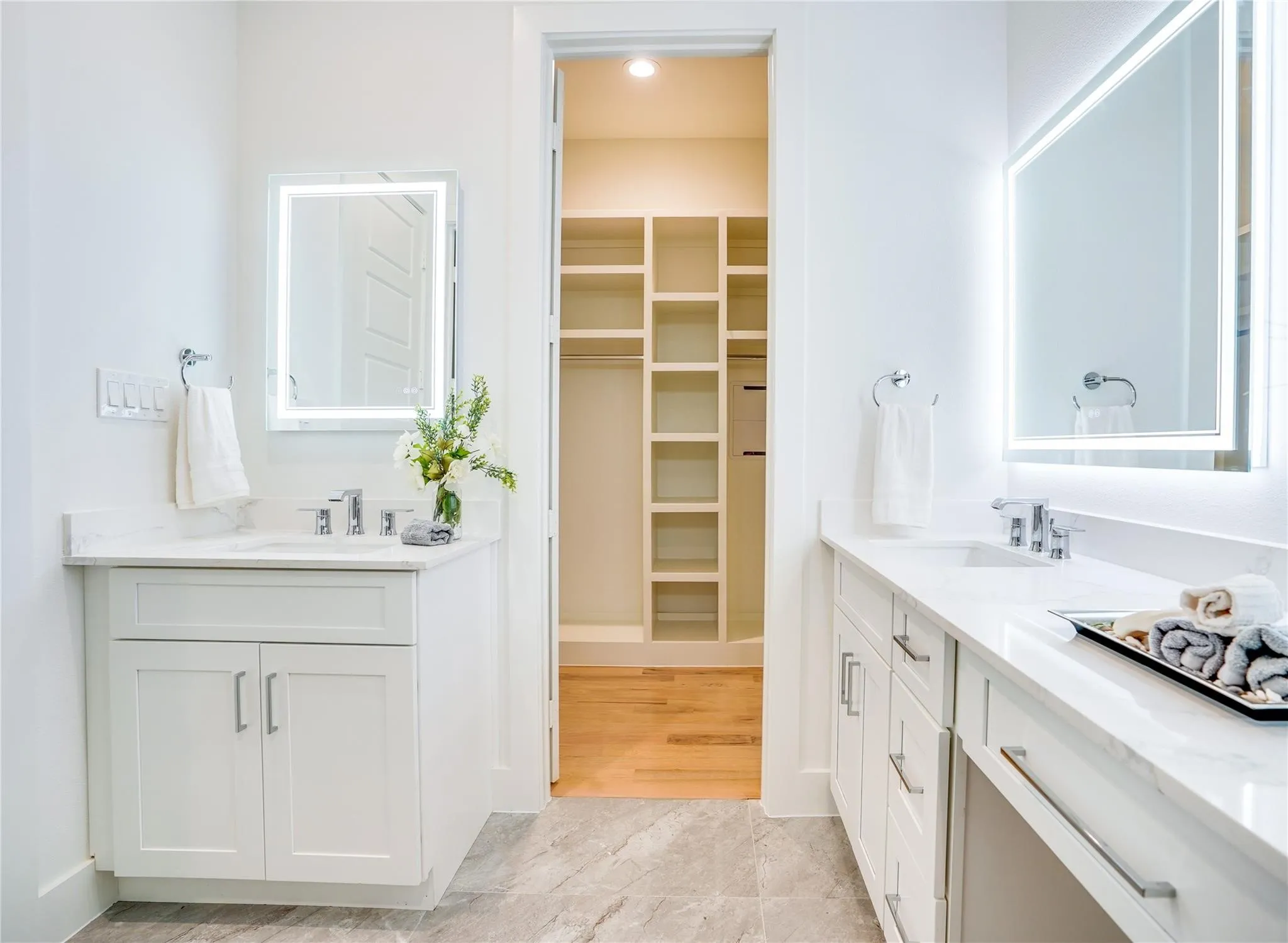 Dual vanity bathroom with light-toned tile flooring