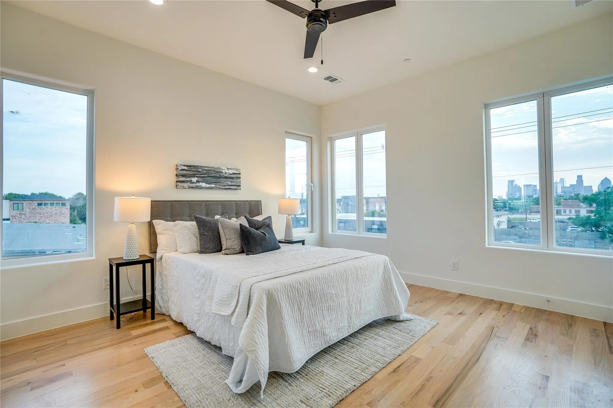 Room featuring expansive windows with cityscape scenery, wood-finish flooring, a contemporary ceiling fan, and recessed lighting