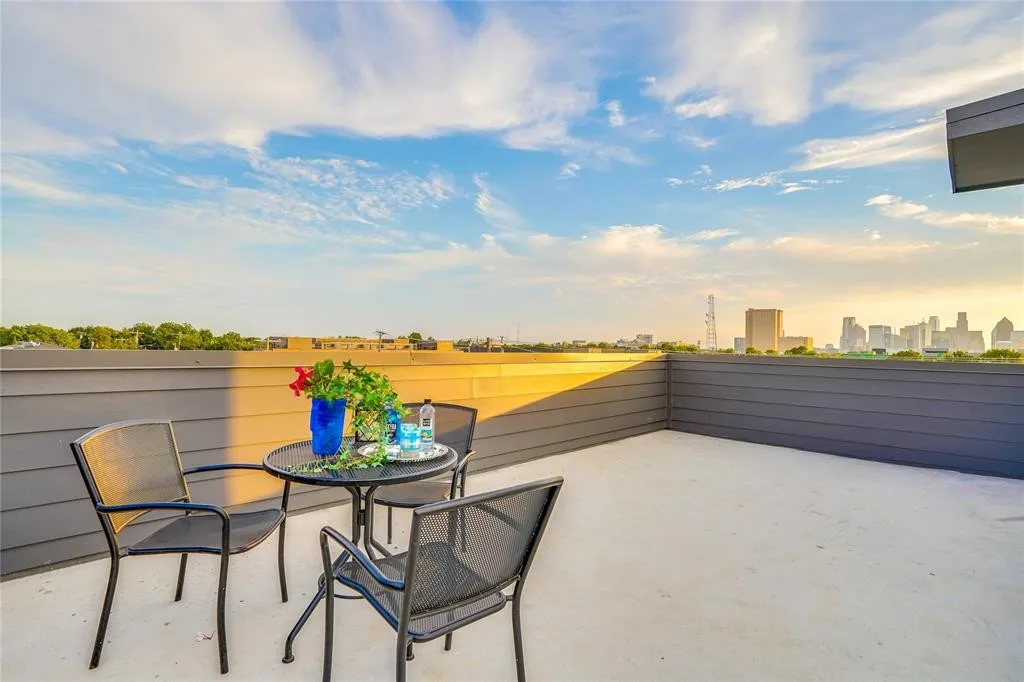 Expansive rooftop deck featuring a light-colored concrete surface and a dark gray horizontal plank fence