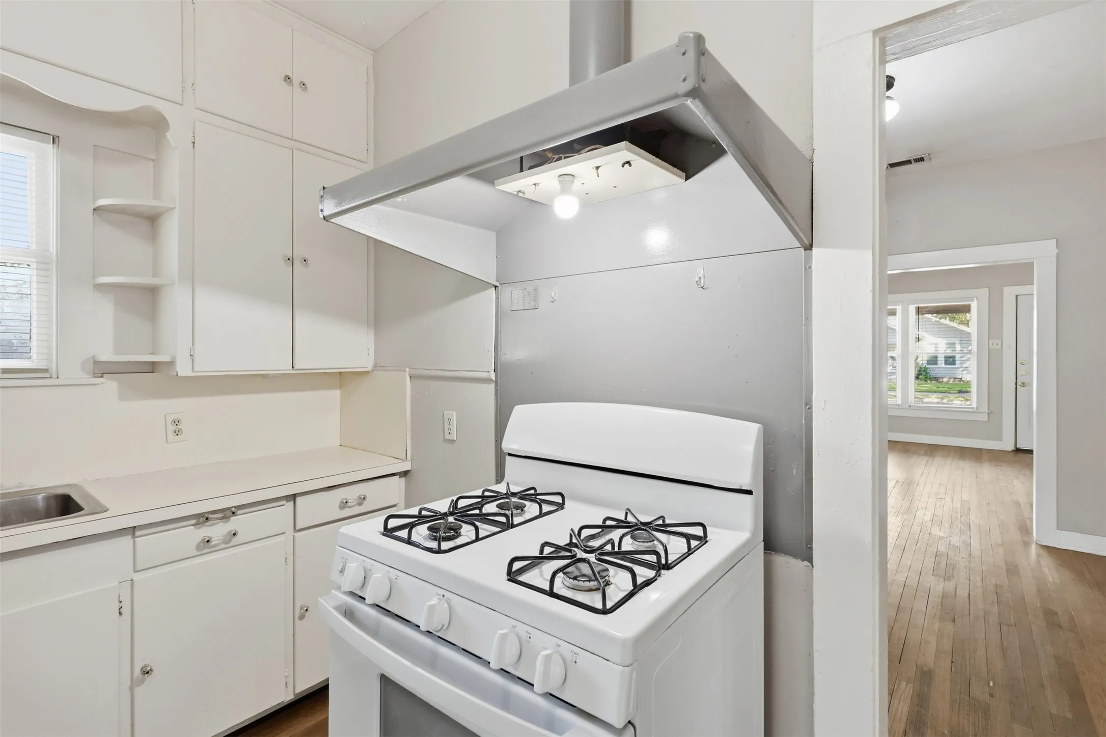Kitchen featuring white cabinetry, a built-in oven with a gas cooktop, a stainless steel sink, and wood-finish flooring
