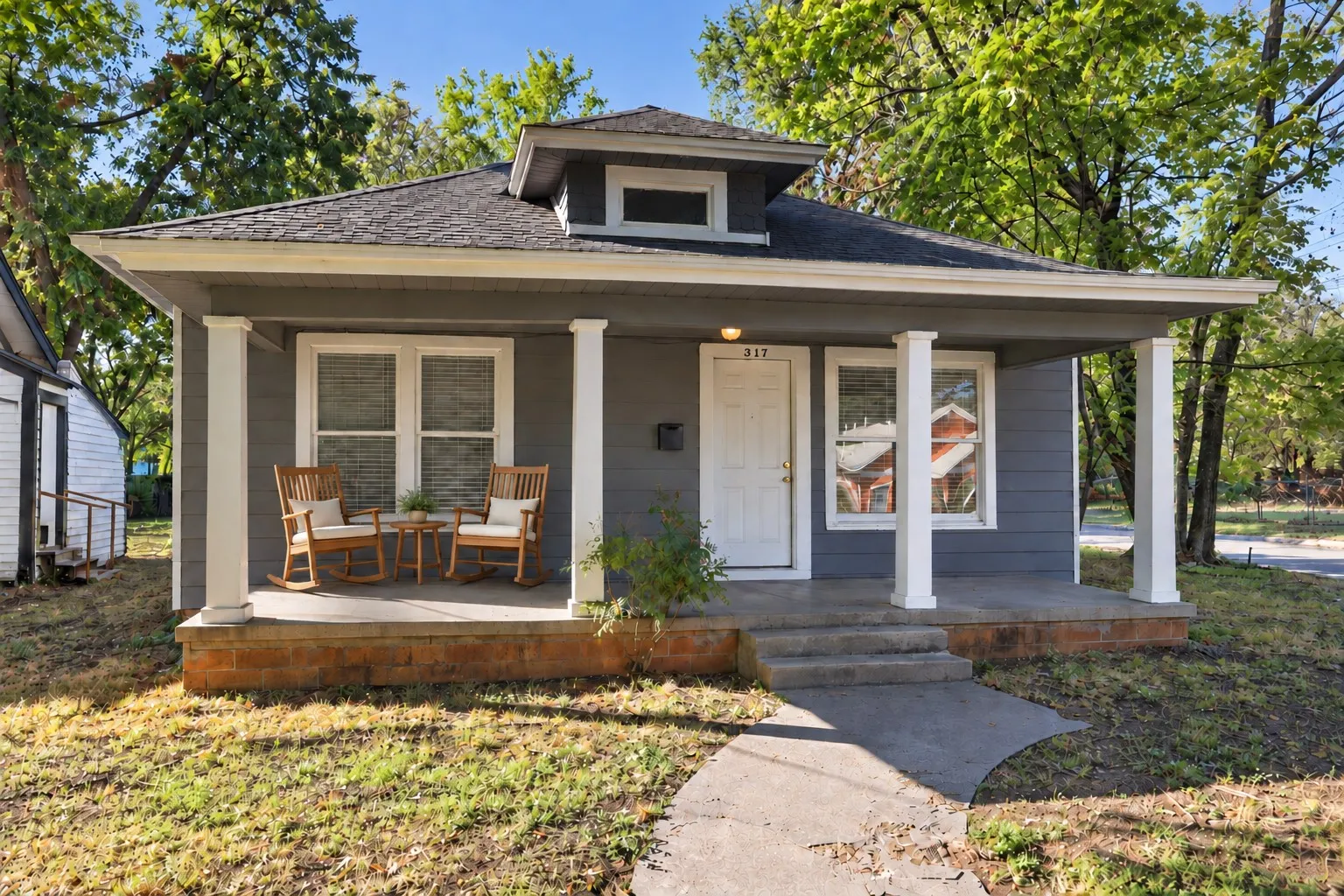 Contemporary exterior featuring a covered porch, white columns, multi-pane windows, and a gray siding finish
