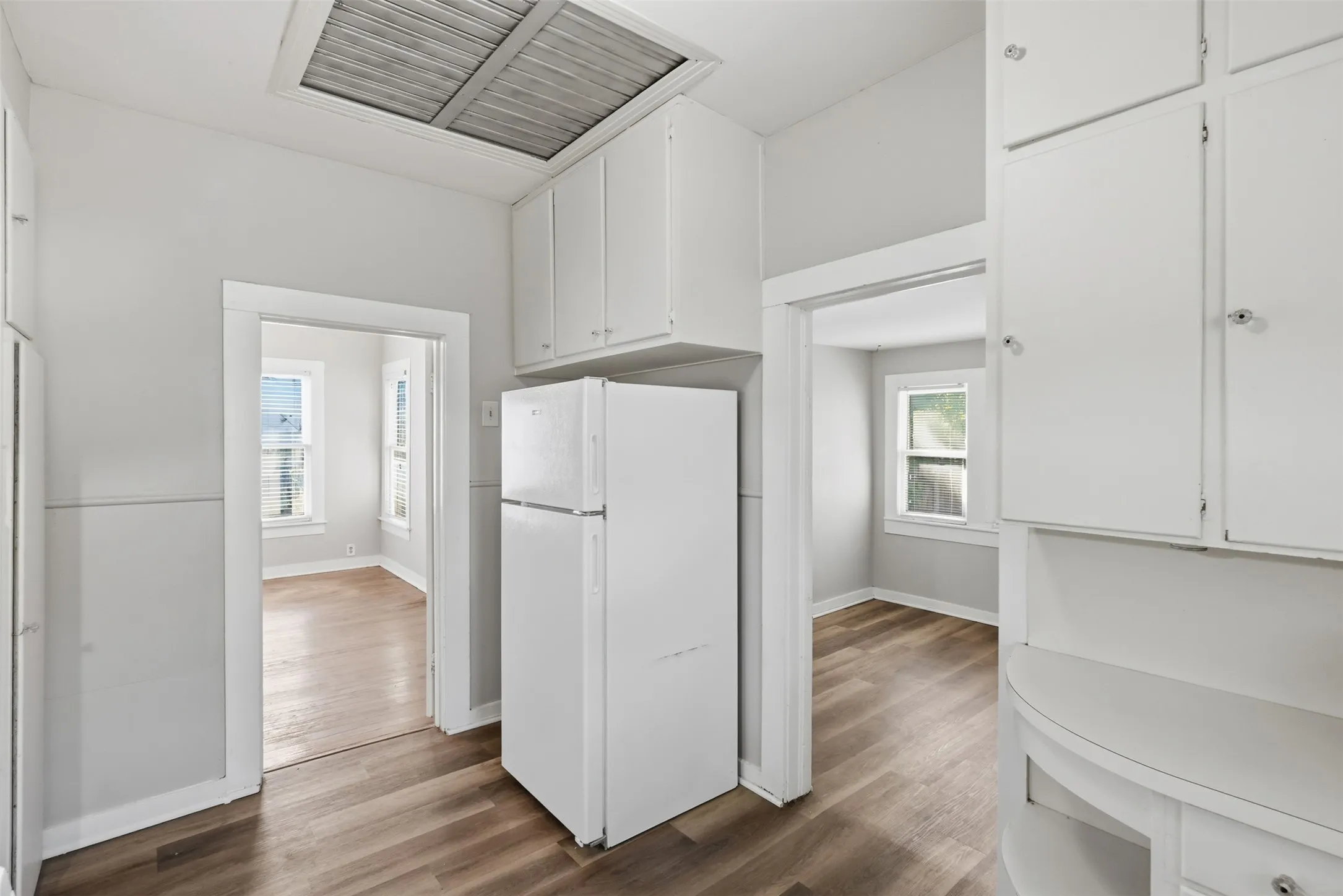 White cabinetry with chrome hardware, wood-finish flooring, and recessed lighting