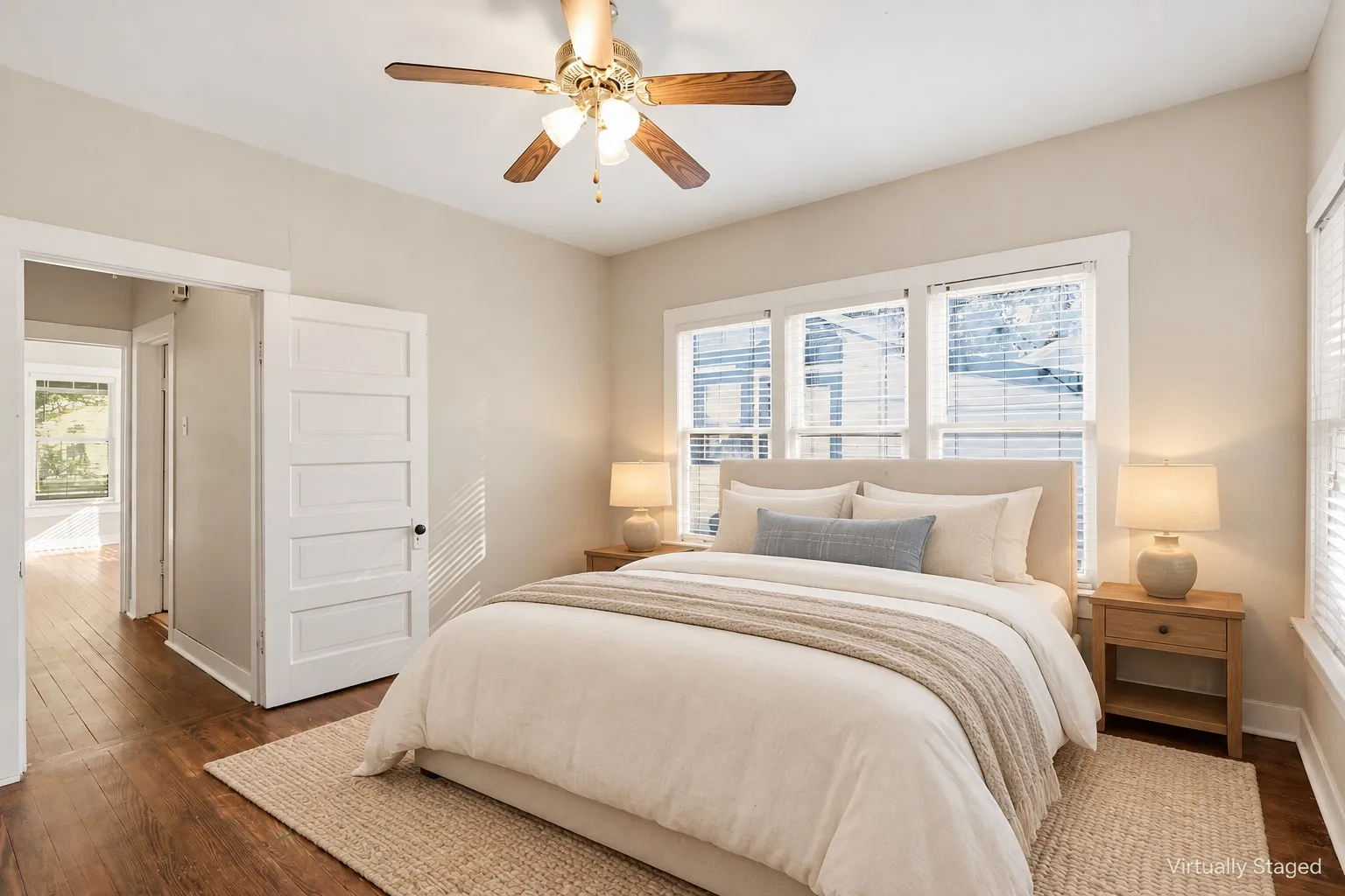 Wood-finish flooring throughout, multiple windows with blinds, ceiling fan, and five-panel interior door