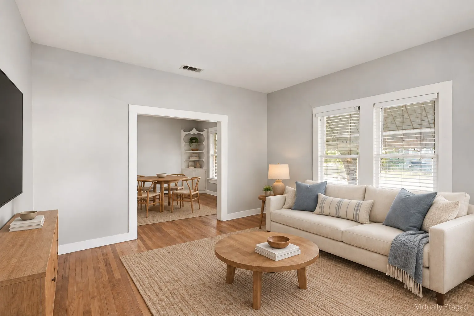 Hardwood flooring throughout, bright white trim, and a framed doorway opening to an additional room
