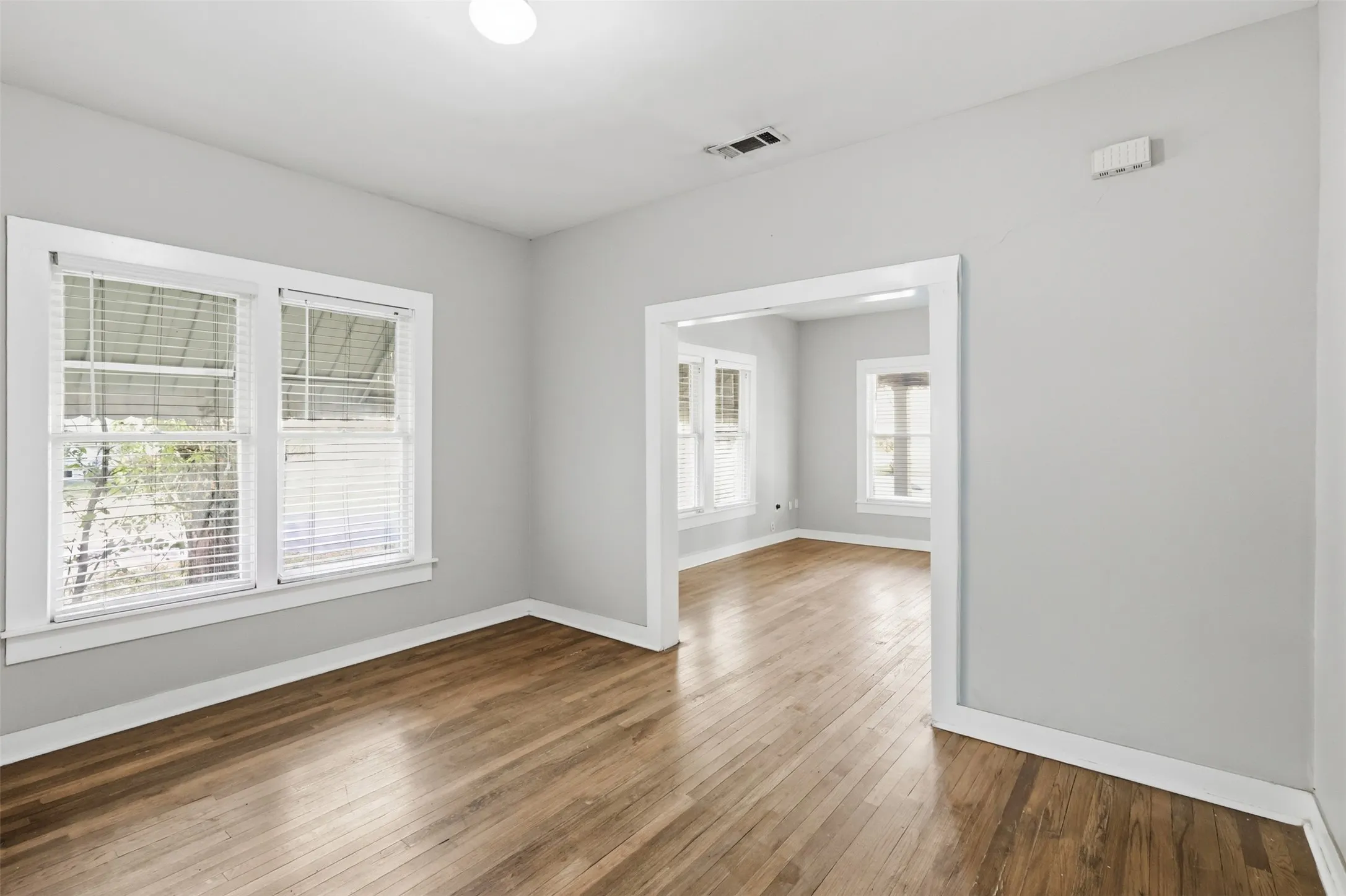 Hardwood flooring throughout, light gray wall finishes, bright white trim, and multiple windows