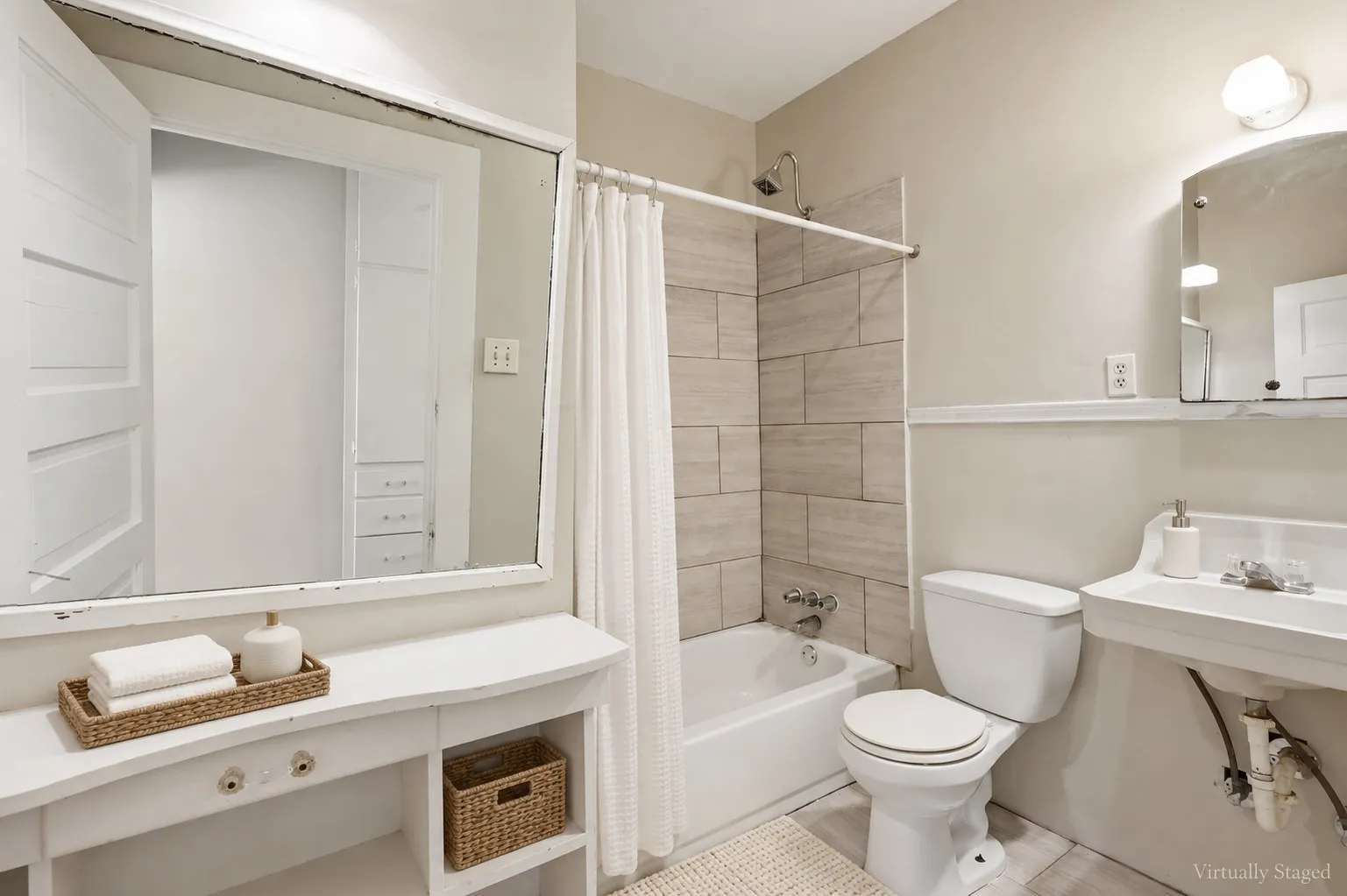 Bathtub with subway tile surround, wall-mounted sink, and vanity with built-in shelving