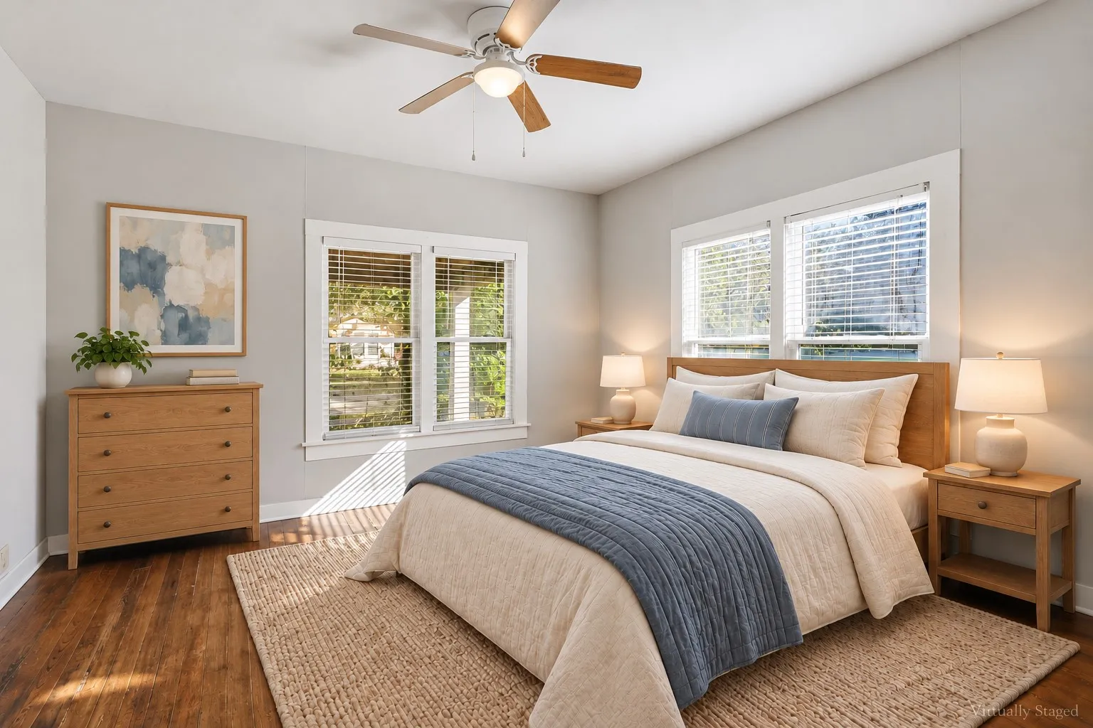Hardwood flooring throughout, two large windows with blinds, a ceiling fan with light, and light-toned wall finishes