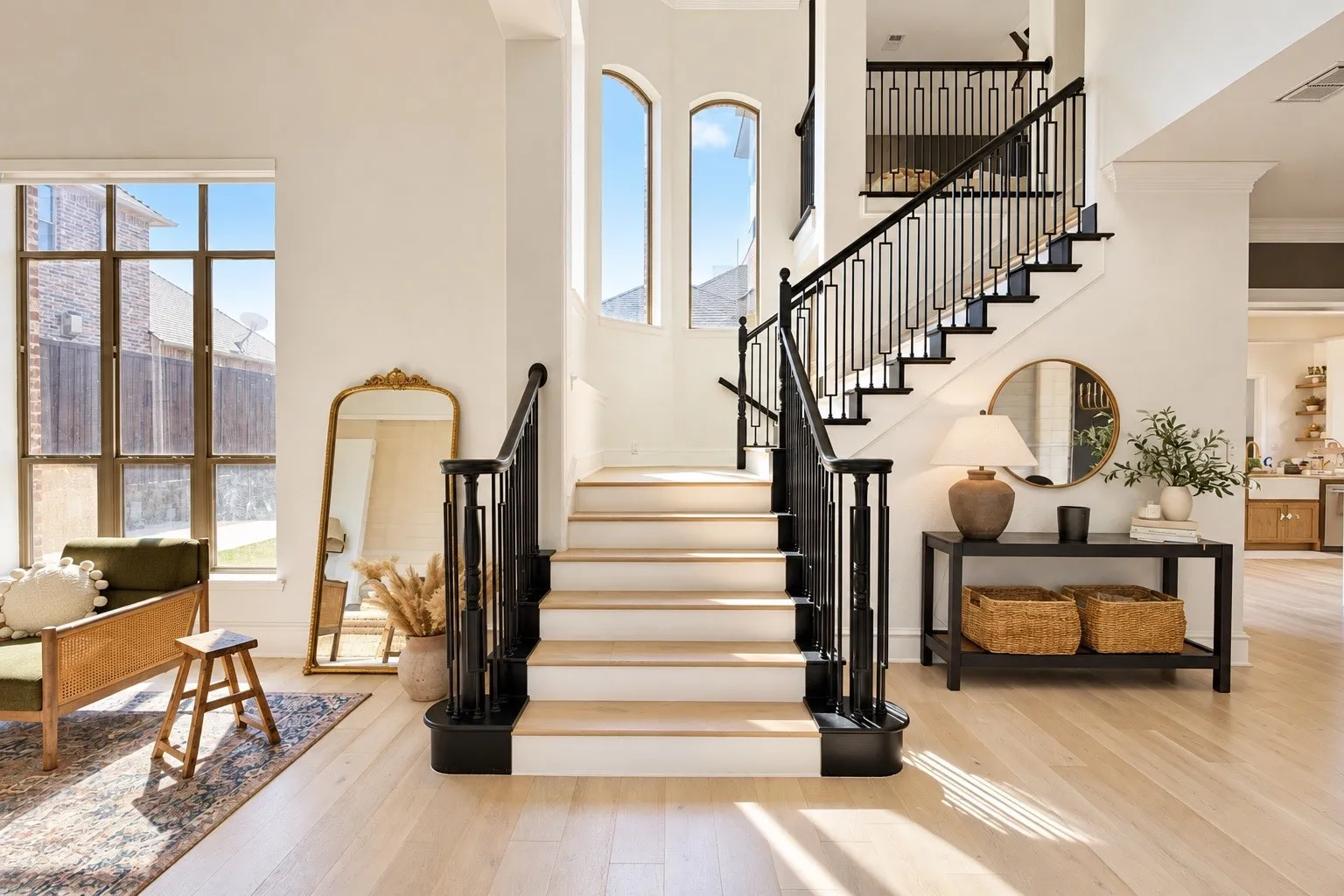 Grand staircase featuring black wrought iron balusters and light wood-finish treads
