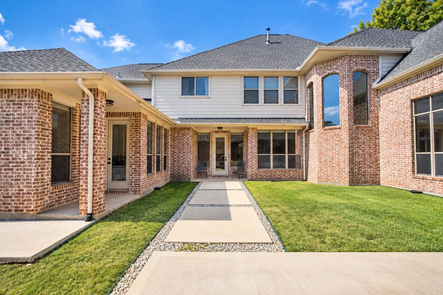 Brick exterior with white siding accents and a dark shingle roof