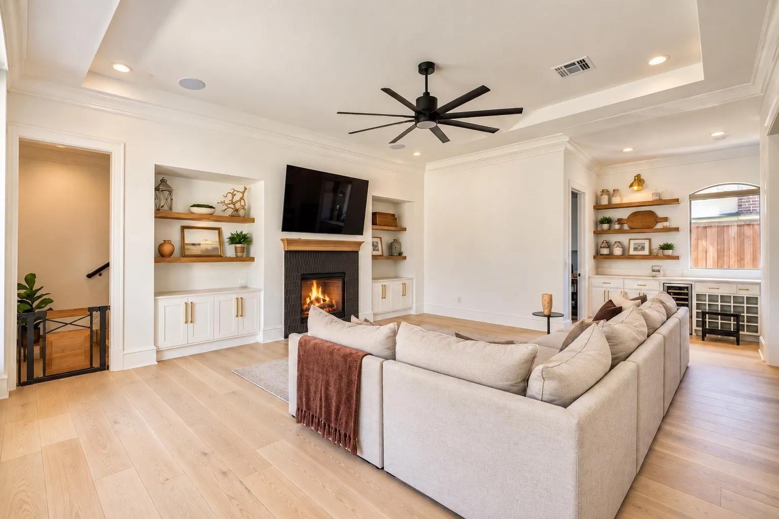Recessed lighting illuminates the living area, featuring wood-finish flooring and a ceiling fan