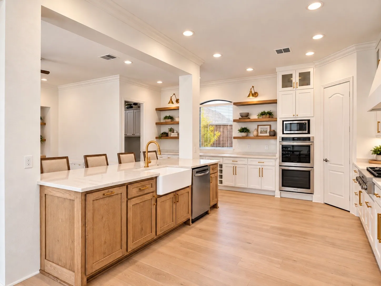 Kitchen featuring a wood-finish island with a farmhouse sink, stainless steel appliances, white cabinetry with gold-finish hardware, and wood-finish flooring