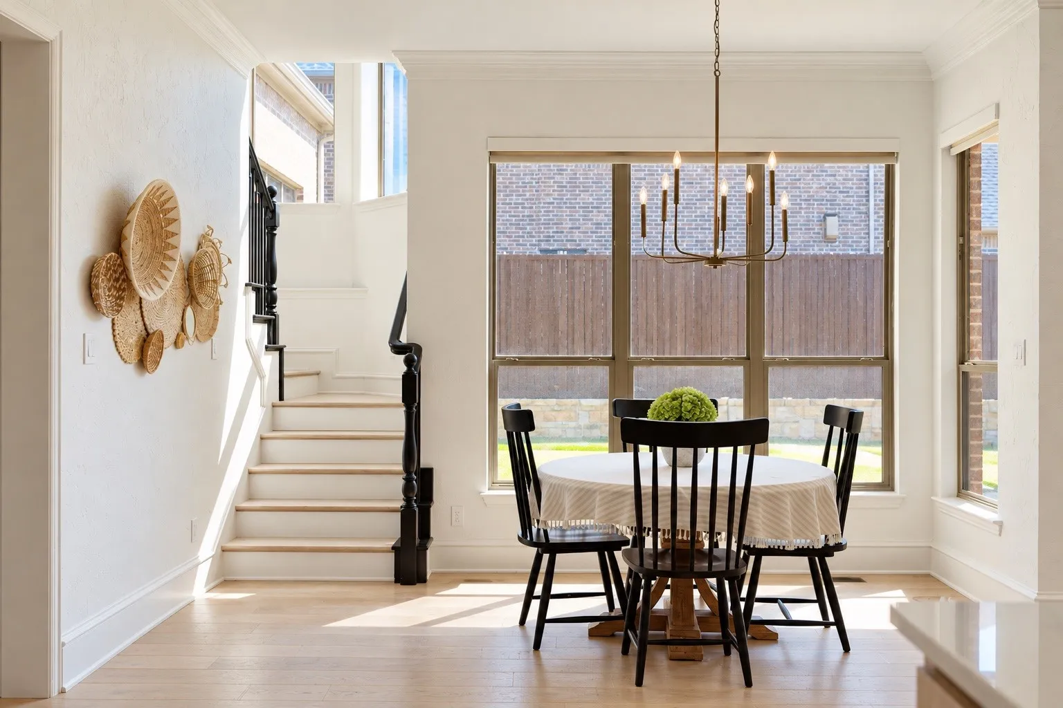 Light wood-finish flooring throughout, white painted walls, white crown molding, and a dark bronze chandelier