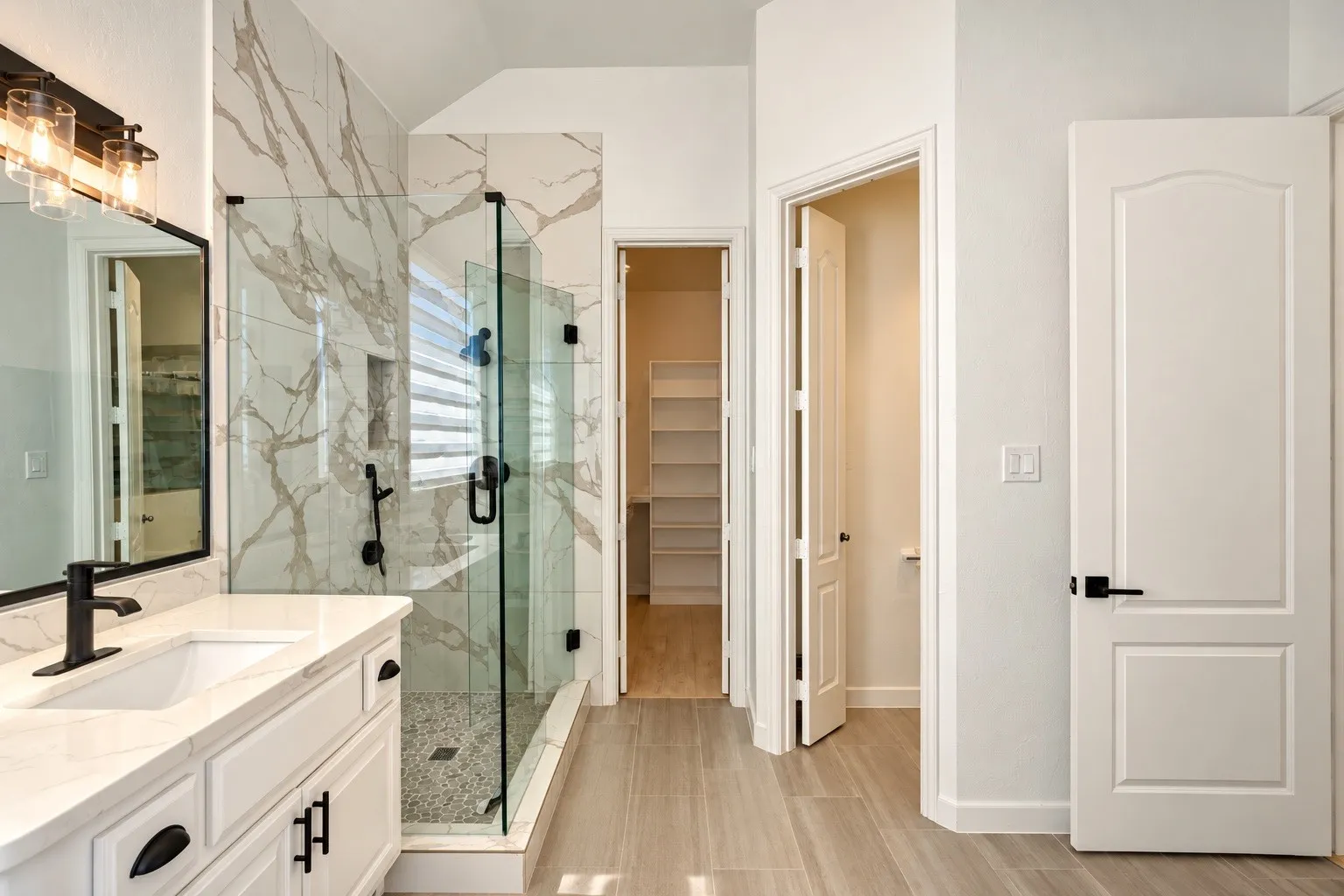 Walk-in shower with glass enclosure and natural stone-look tiling