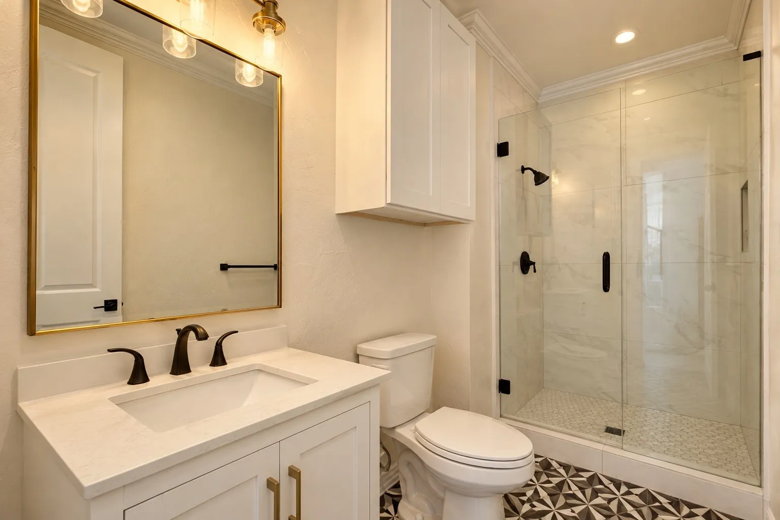 White shaker vanity with gold hardware, bronze-finish faucet, and a rectangular undermount sink