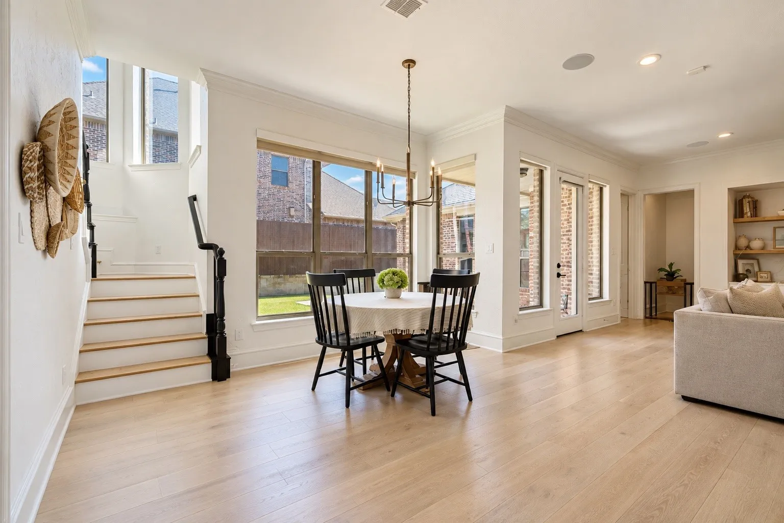 Wood-finish flooring, staircase with dark wood newel posts, multiple windows, recessed ceiling lighting, and built-in shelving