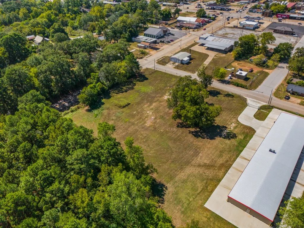 Expansive open lot featuring partial tree coverage and adjacent to a paved road