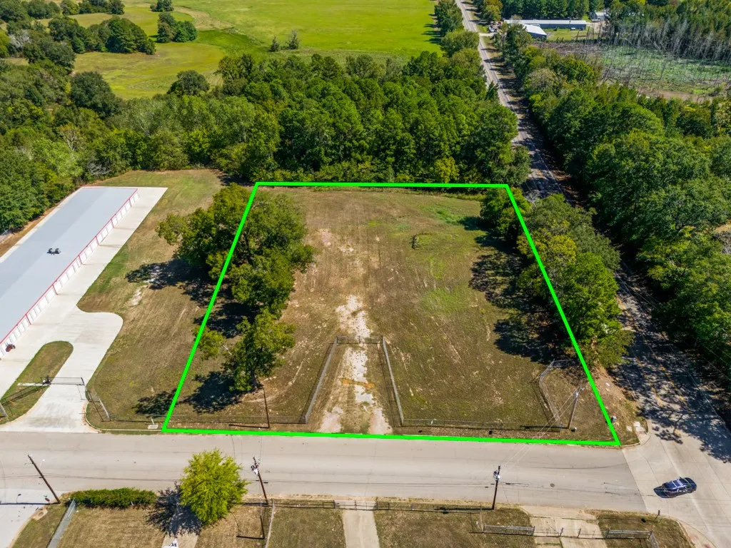 Expansive lot with partial tree coverage, adjacent to a paved road