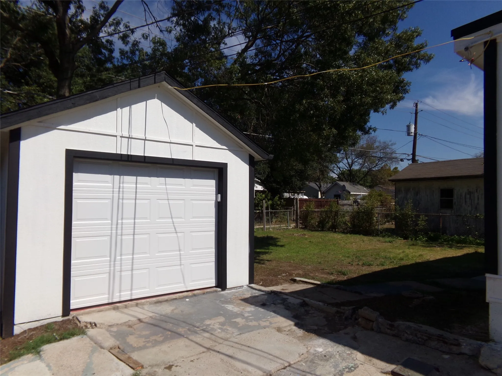 Detached garage with a white paneled door, black trim, and a gabled roof