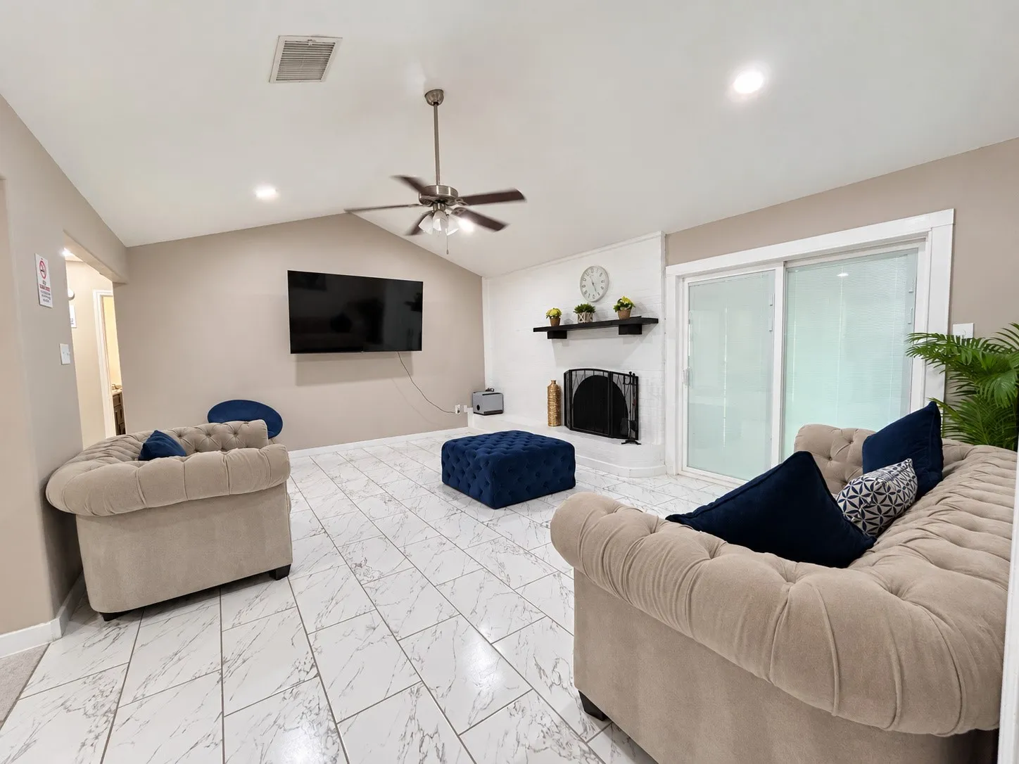 Vaulted ceiling with a ceiling fan, white tile flooring, fireplace with a mantel, sliding glass door, and recessed lighting